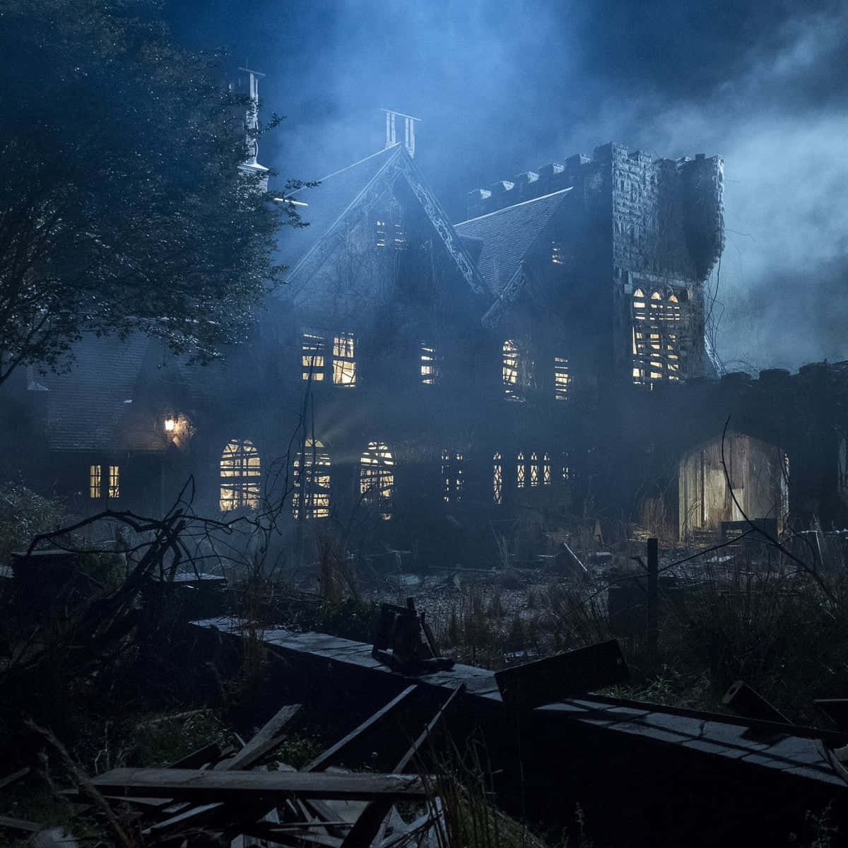 Haunted House 桌布 壁紙 — 一座詭異美麗的哥德式大宅在暴風雨的夜空下矗立於廢墟中，破窗透出詭異的光芒。