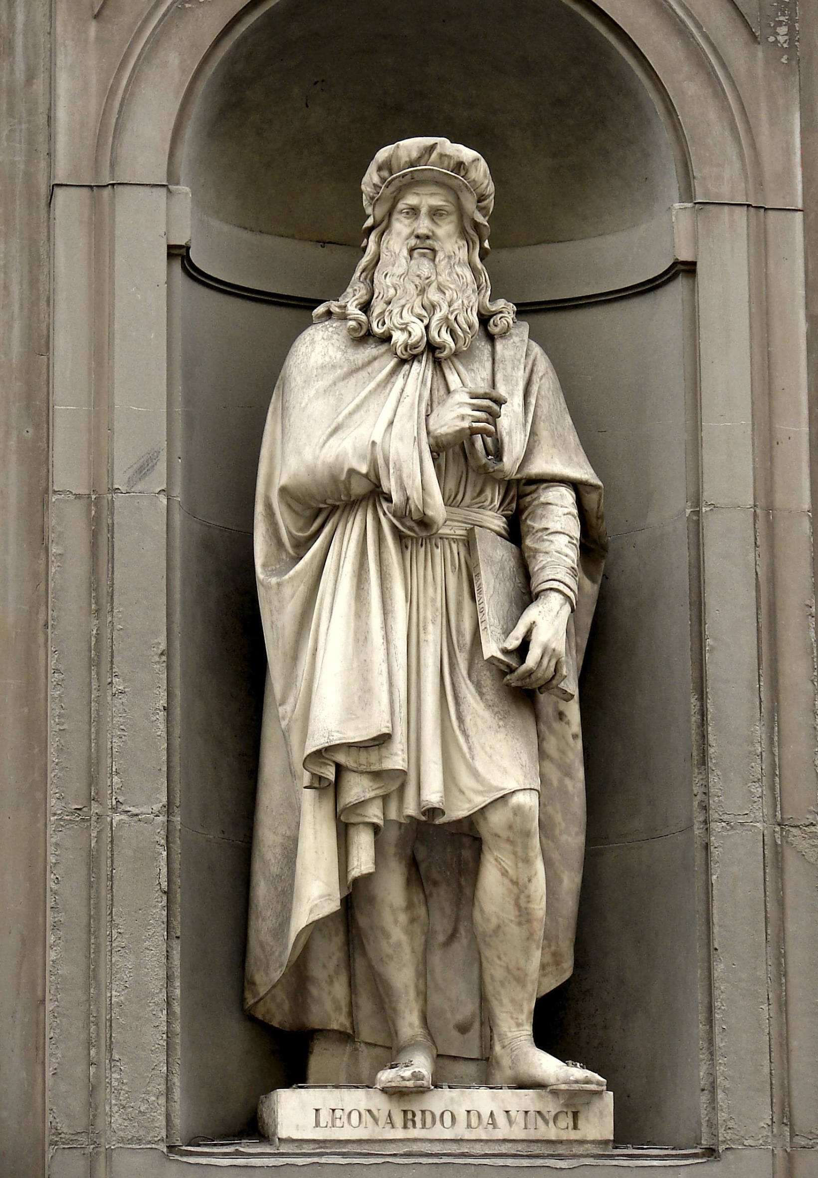 Leonardo Da Vinci 桌布 壁紙 — 一座詳細的列奧納多·達·芬奇石像矗立在經典的拱形壁龕中，下方刻有他的名字。