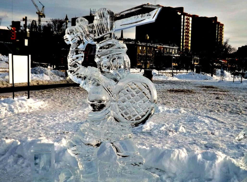Ice Sculpture 桌布 壁紙 — 一座身穿盔甲的騎士冰雕高聳矗立在積雪的城市廣場上，背景有建築物和起重機。
