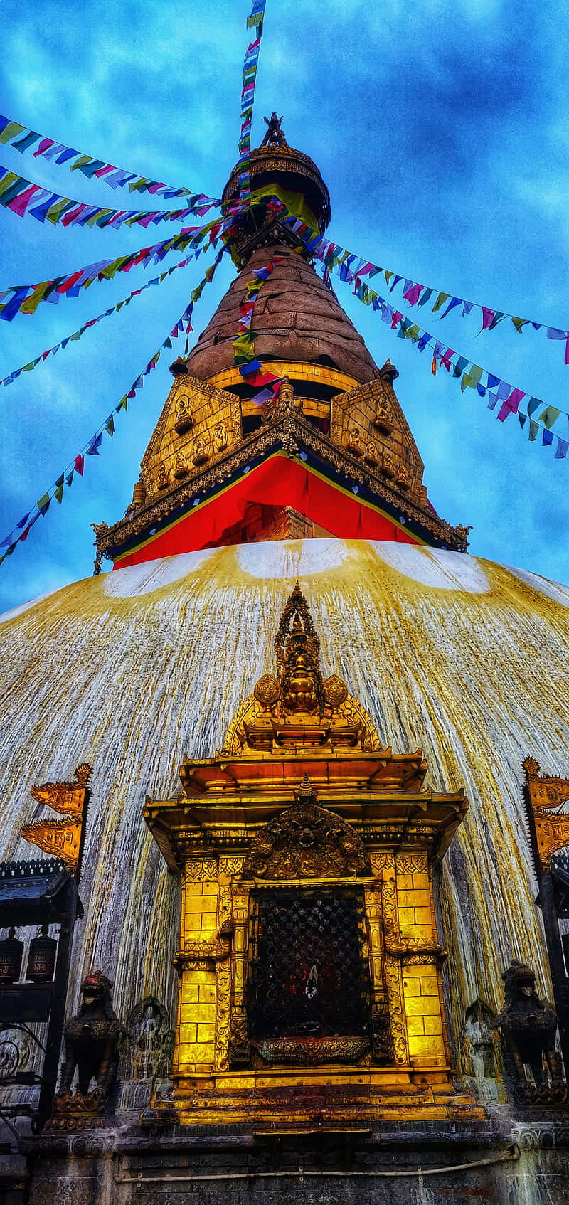 桌布 壁紙 — 一座金色佛塔，經幡在戲劇性光線下於鮮豔藍天中飄揚。