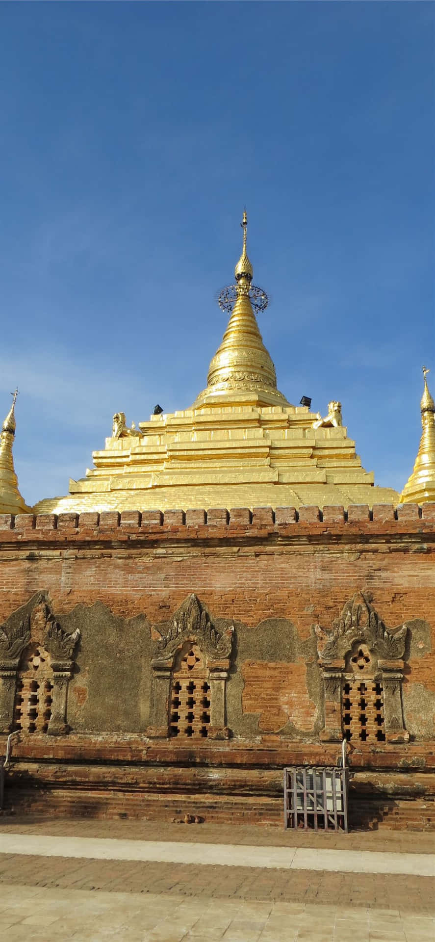 Hindu Temple 桌布 壁紙 — 一座金色寶塔，磚砌工藝精緻，在清澈的藍天下高聳矗立。