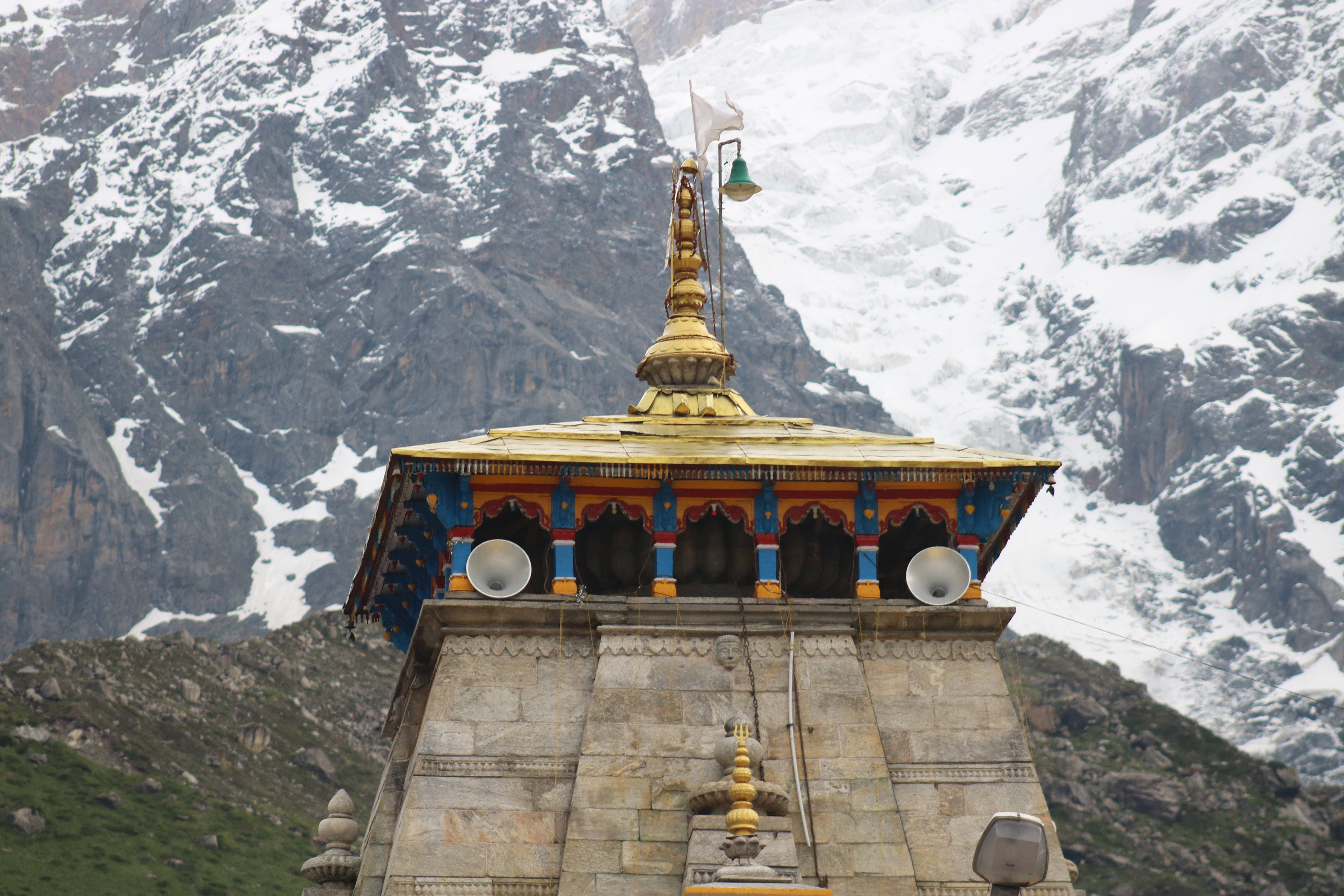 Kedarnath 桌布 壁紙 — 一座金色屋頂、色彩繽紛拱門的寺廟，以白雪覆蓋的喜馬拉雅山峰為背景。