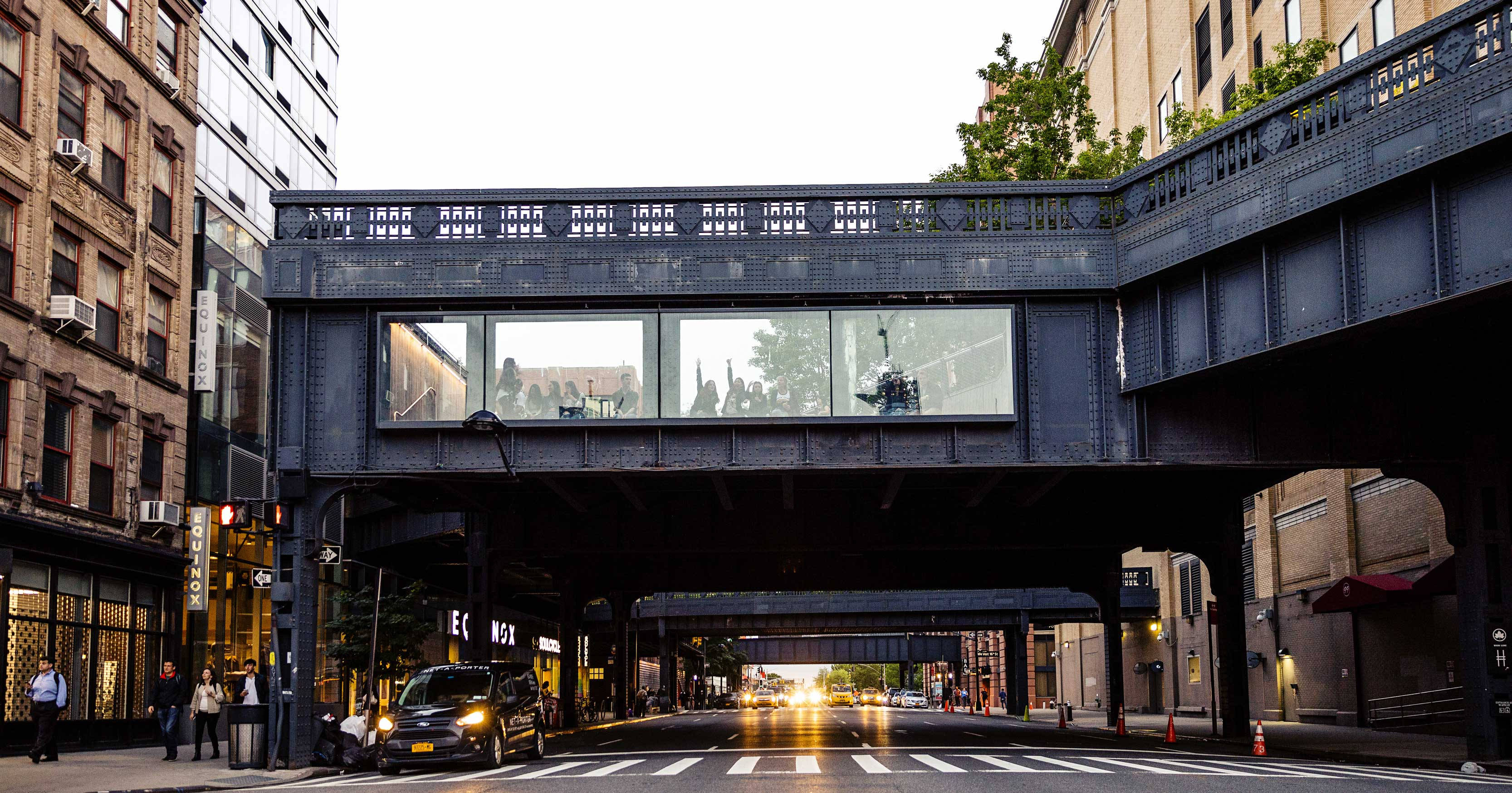 New York 桌布 壁紙 — 一座鋼製高架火車橋橫跨黃昏時分的城市街道，下方有行人和汽車，上方玻璃窗中有倒影。