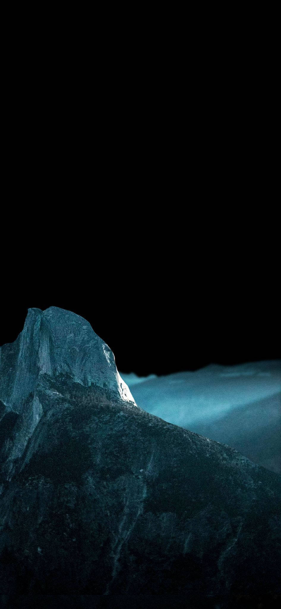 Winter 桌布 壁紙 — 一座陡峭的山峰在漆黑天空和霧氣瀰漫的山谷上方散發著冰冷的藍光。