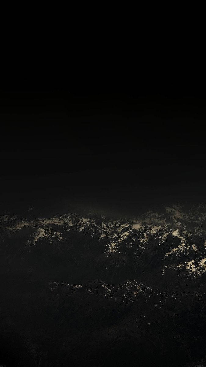 夜空 桌布 壁紙 — 一座陡峭的山脈，白雪覆蓋的山峰在深邃的黑色夜空中微微發光。