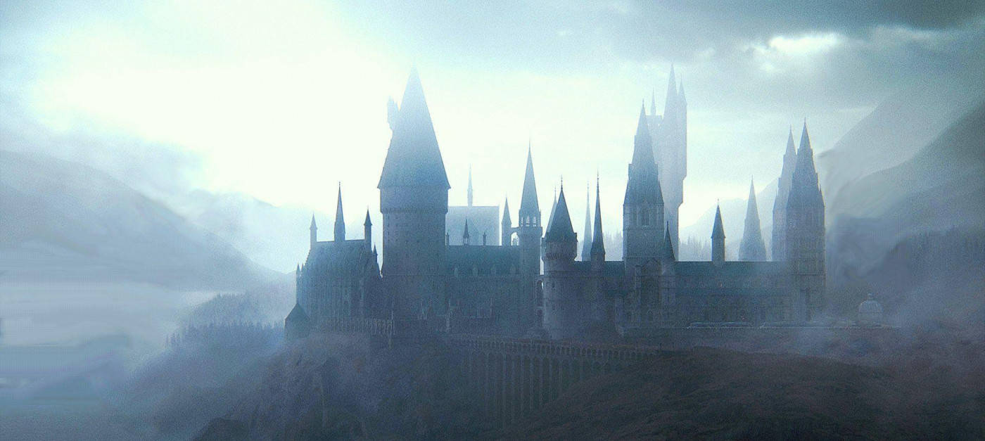 Hogwarts Castle 桌布 壁紙 — 一座雄偉的哥德式城堡坐落在霧氣瀰漫的懸崖上，高聳的尖塔和塔樓在陰雲密布的天空下籠罩在迷霧中。