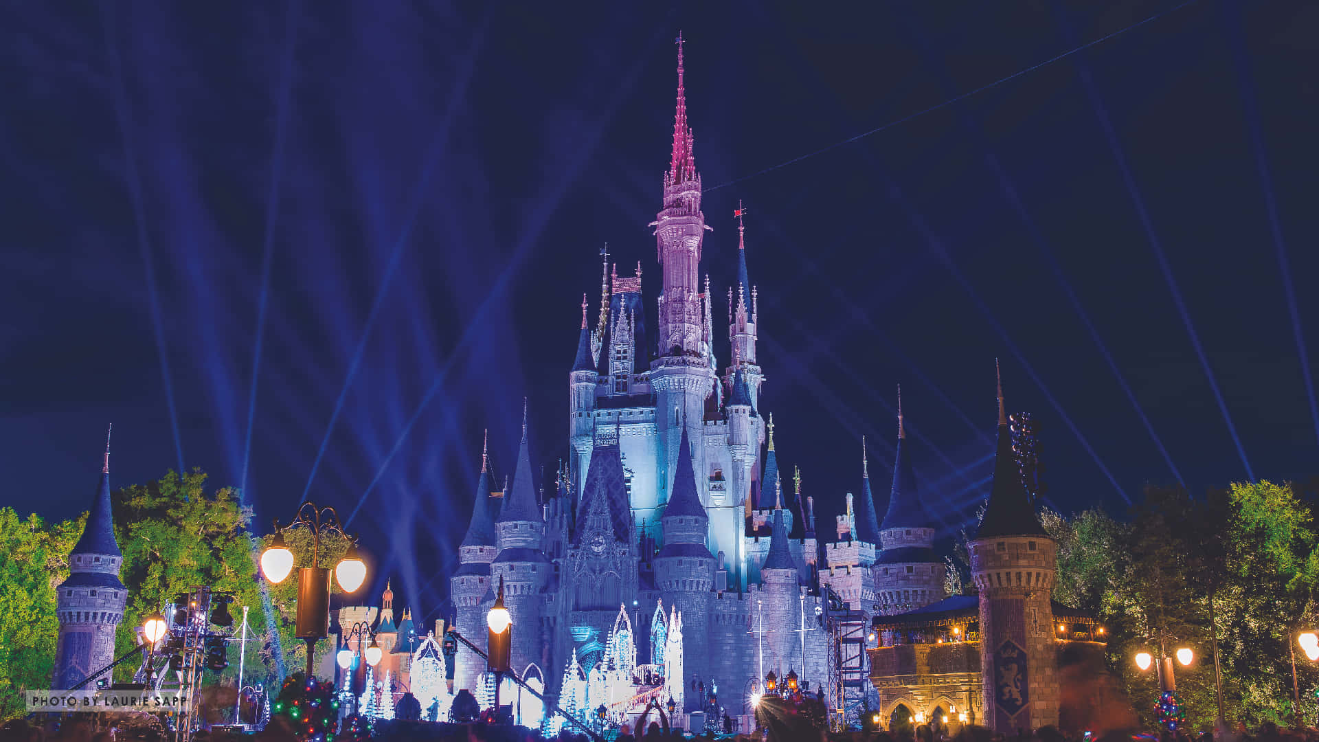迪士尼 桌布 壁紙 — 一座雄偉的城堡在漆黑的夜空下被鮮豔的藍色聚光燈照亮，下方有發光的燈籠。