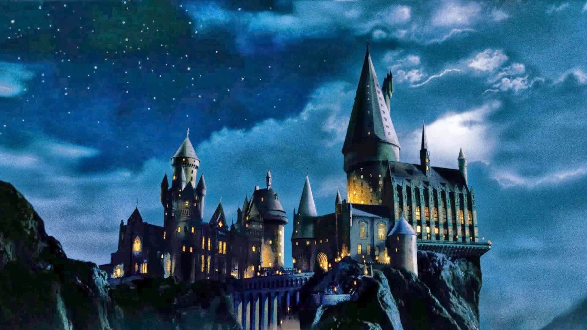 Christmas At Hogwarts 桌布 壁紙 — 一座雄偉的城堡坐落在懸崖上，星空下，發光的窗戶照亮了哥德式塔樓。