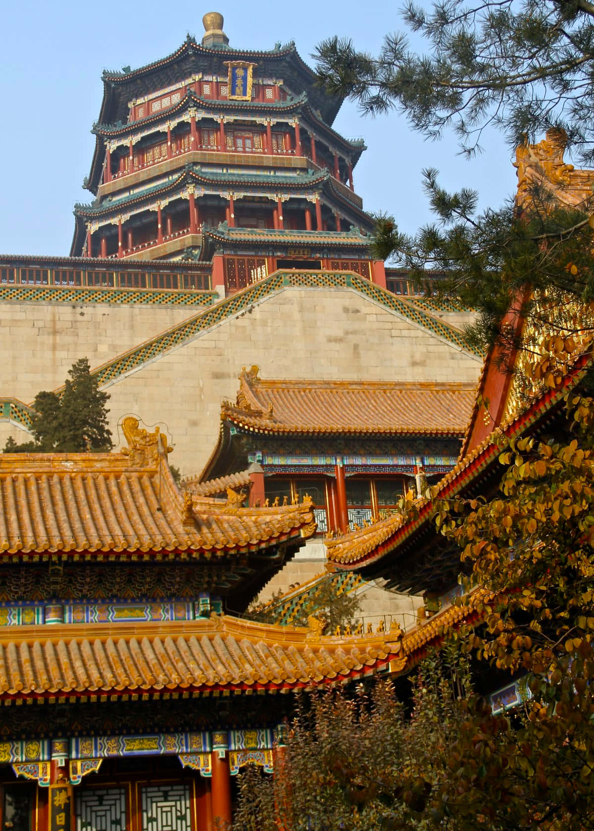 建築 桌布 壁紙 — 一座雄偉的多層中式寶塔，金色屋頂和紅色柱子，聳立在石砌平台上，周圍環繞著秋葉。