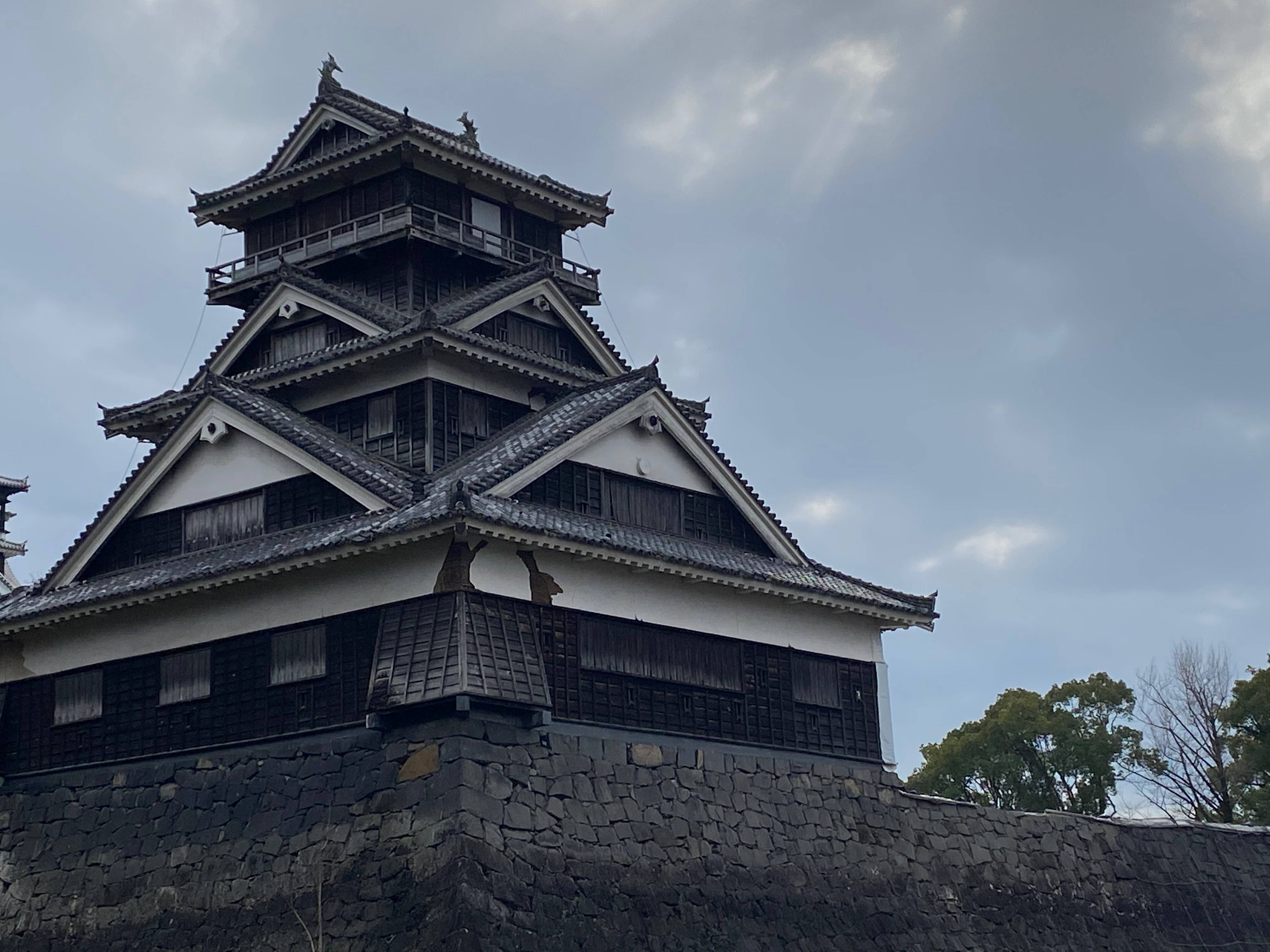 旅行 桌布 壁紙 — 一座雄偉的多層日本城堡塔樓，深色木材和白色牆壁，聳立在多雲的天空下。