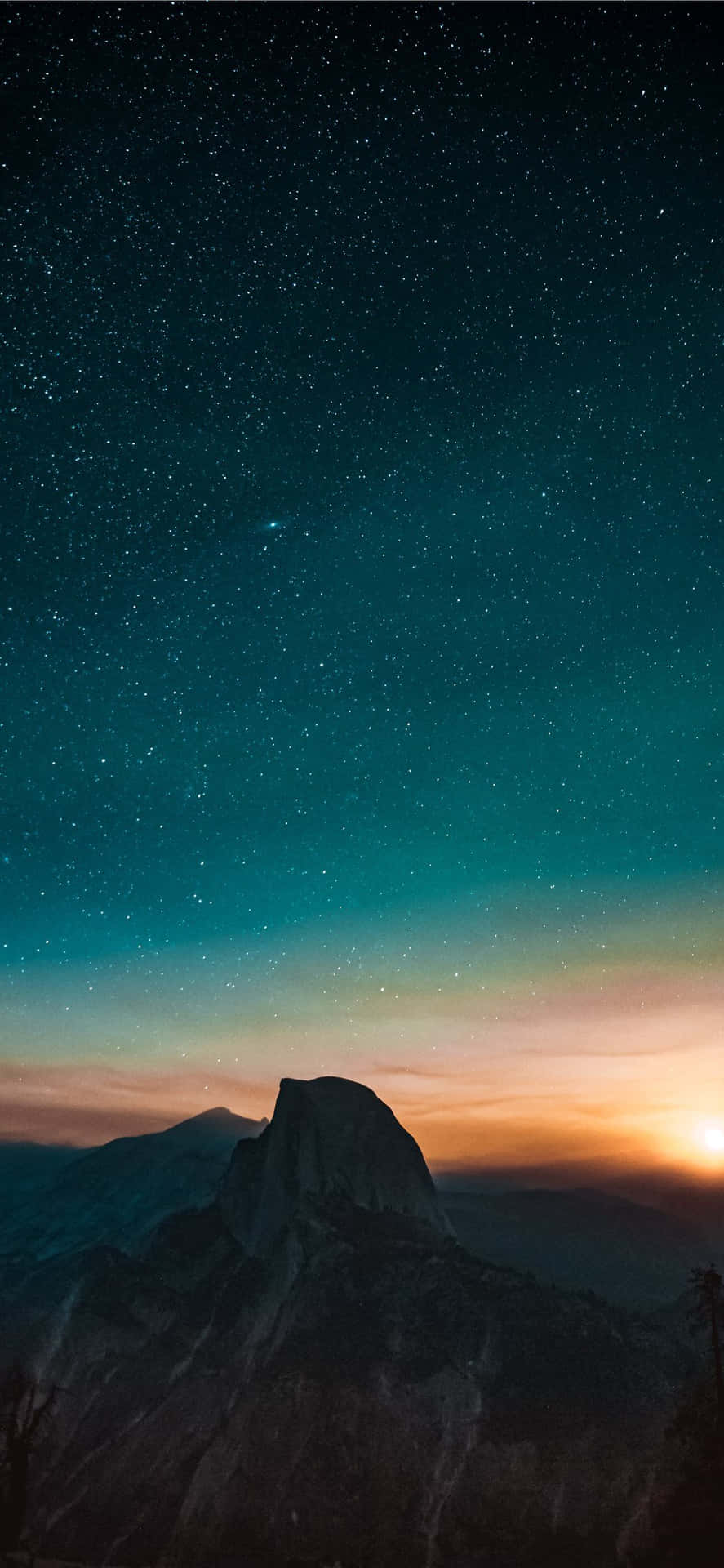 iPhone 11 Pro 桌布 壁紙 — 一座雄偉的山峰在充滿無數星星和發光地平線的充滿活力的暮色天空中形成剪影。