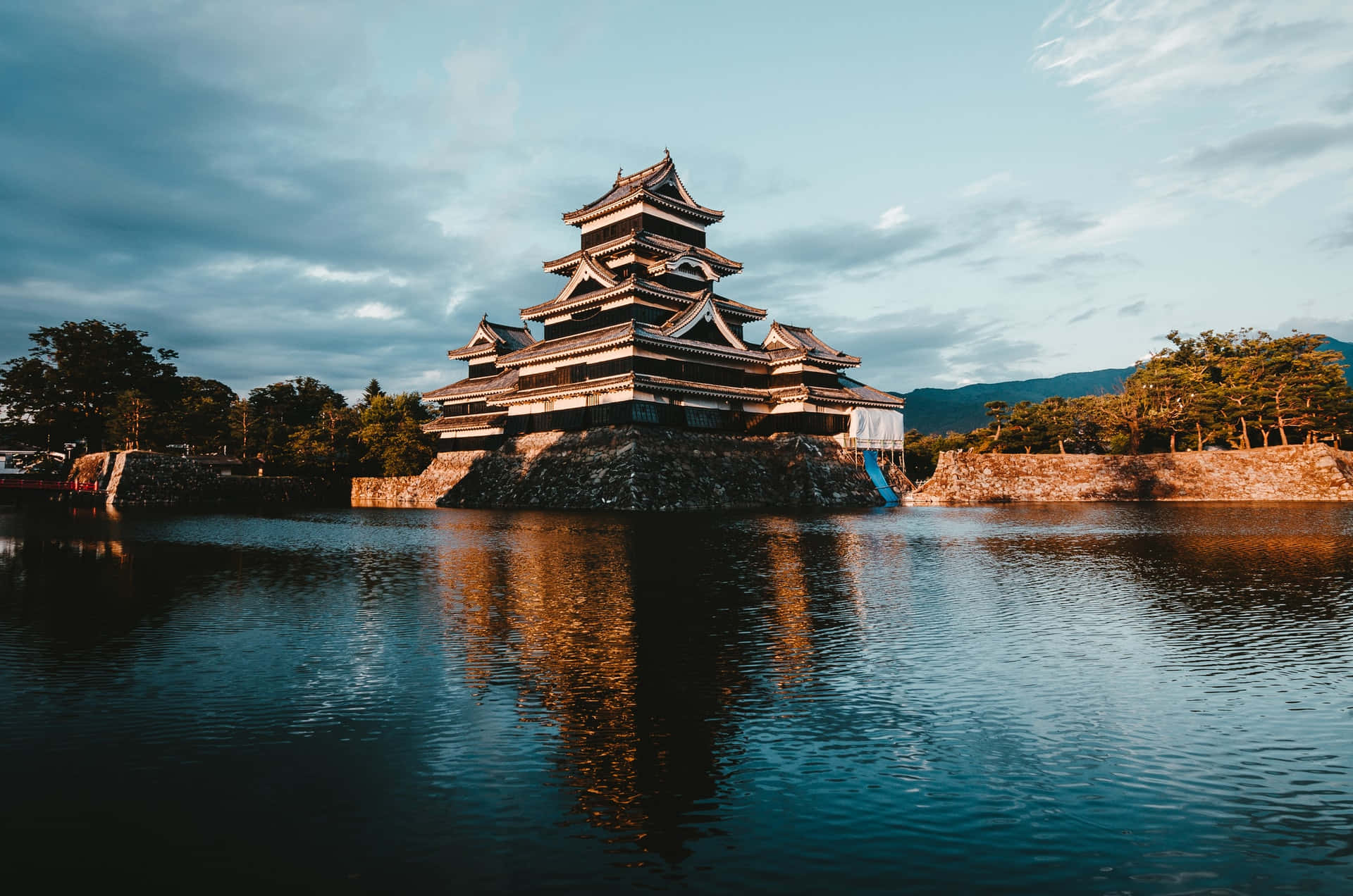 水 桌布 壁紙 — 一座雄偉的日本城堡，擁有層疊屋頂，在柔和暮色天空下倒映在平靜的水面上。