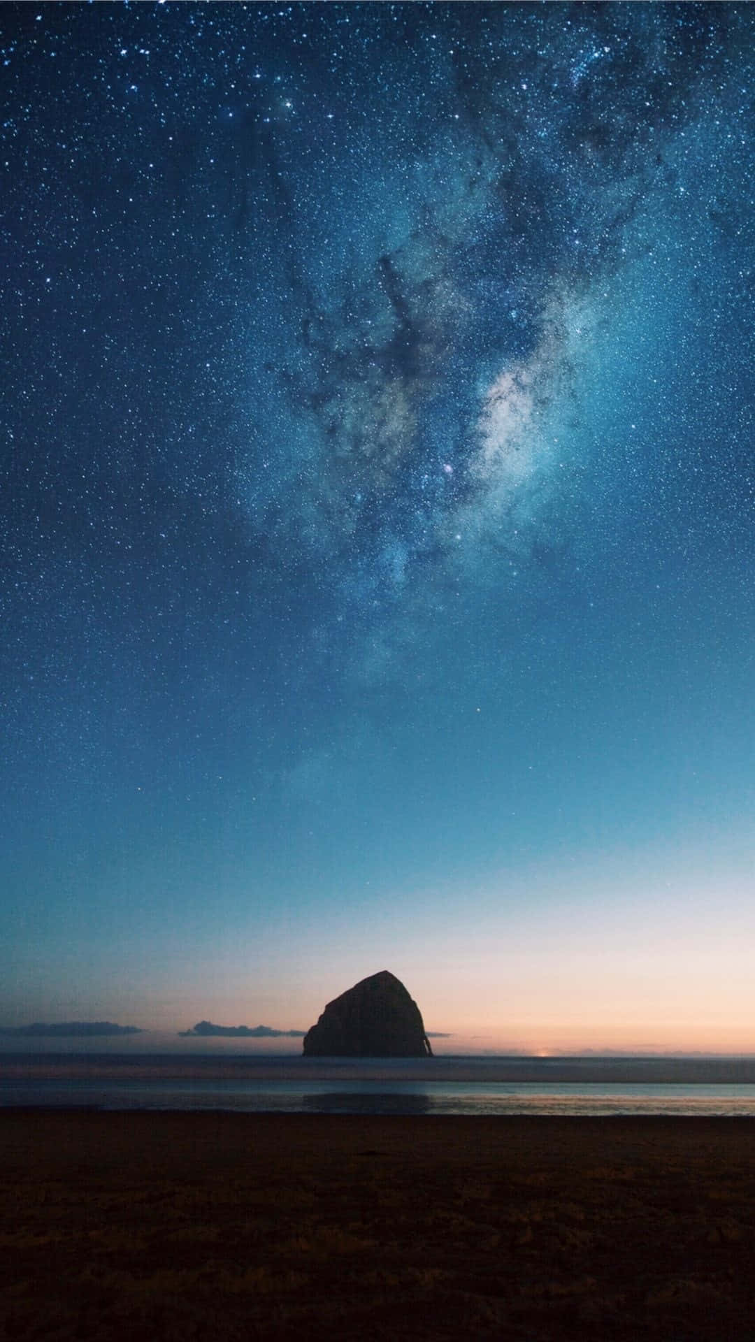 Calming iPhone 桌布 壁紙 — 一座雄偉的海蝕柱在佈滿銀河和星星的暮色天空中呈現剪影。