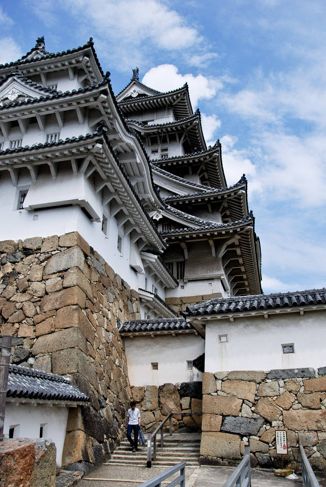Himeji Castle 桌布 壁紙 — 一座雄偉的白色日本城堡，層層疊疊的黑色屋頂，在藍天白雲的映襯下巍然聳立。