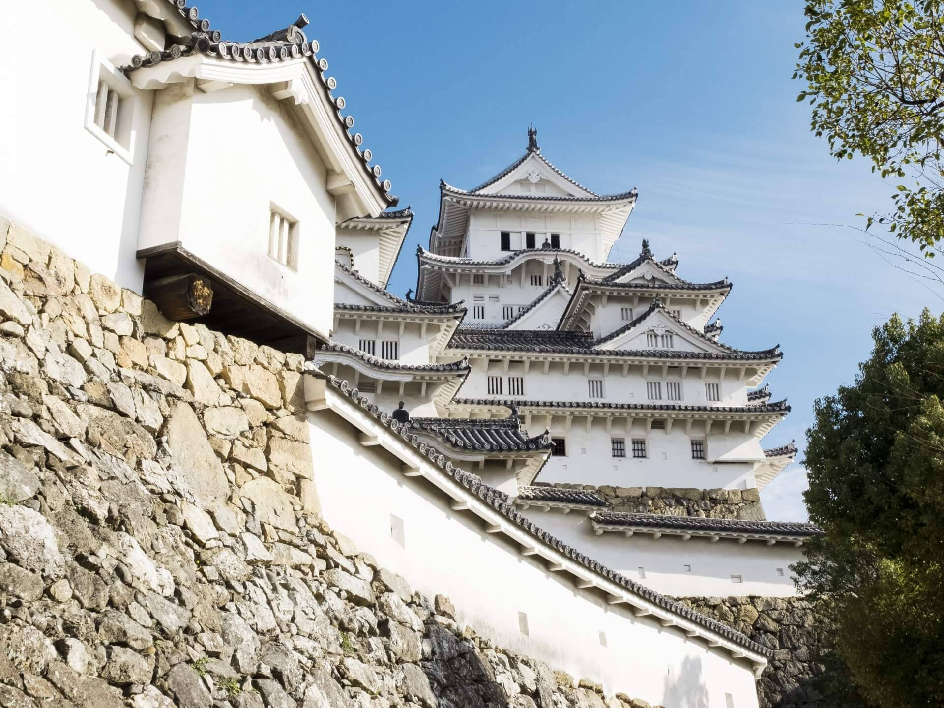Himeji Castle 桌布 壁紙 — 一座雄偉的白色日本城堡，擁有分層屋頂和石牆，在晴朗的藍天下高高聳立。