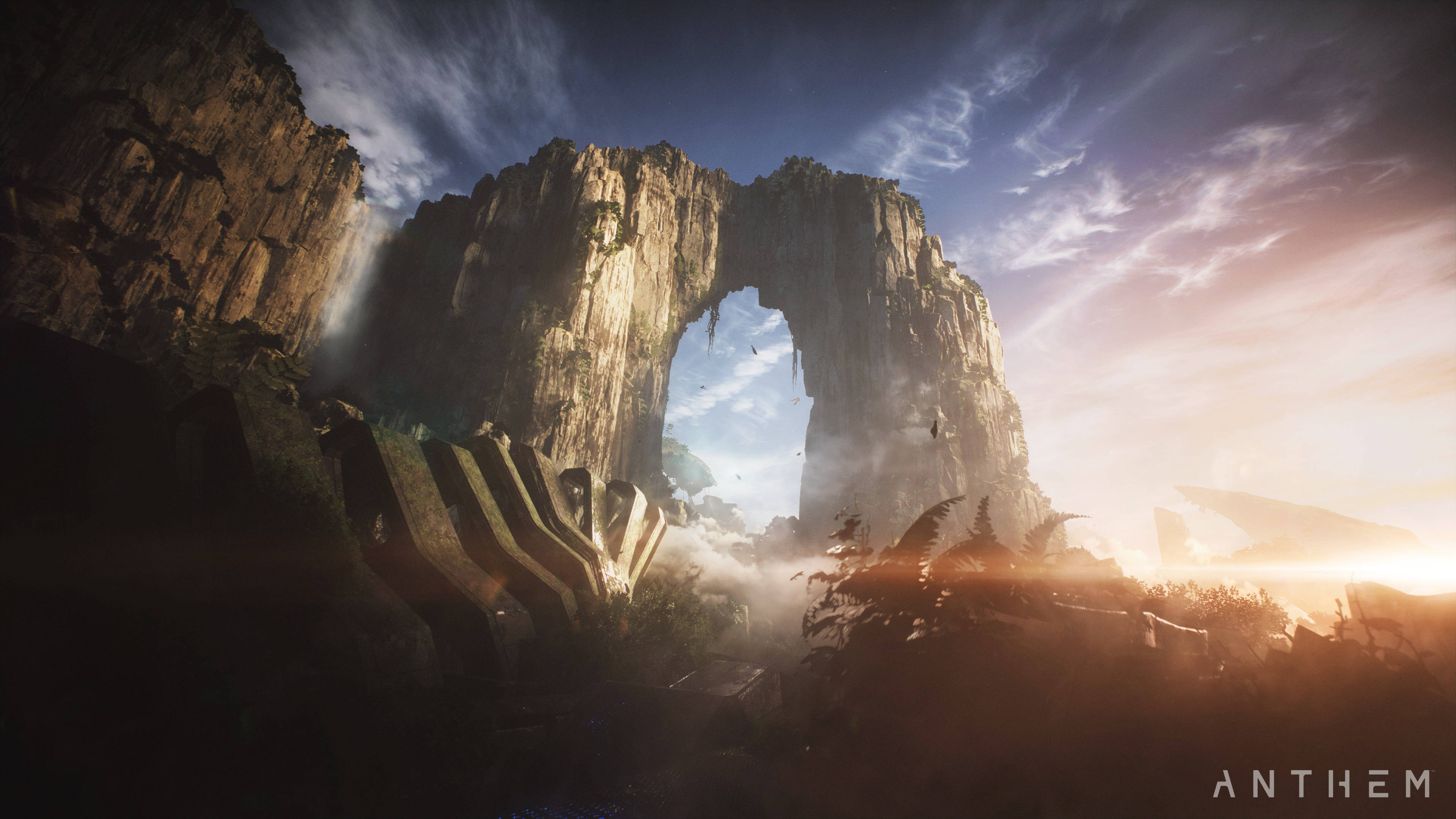 anthem 4K 桌布 壁紙 — 一座雄偉的石拱門聳立在日落時分的霧氣山谷之上，溫暖的光線在崎嶇的懸崖和古代遺跡上投下長長的陰影。