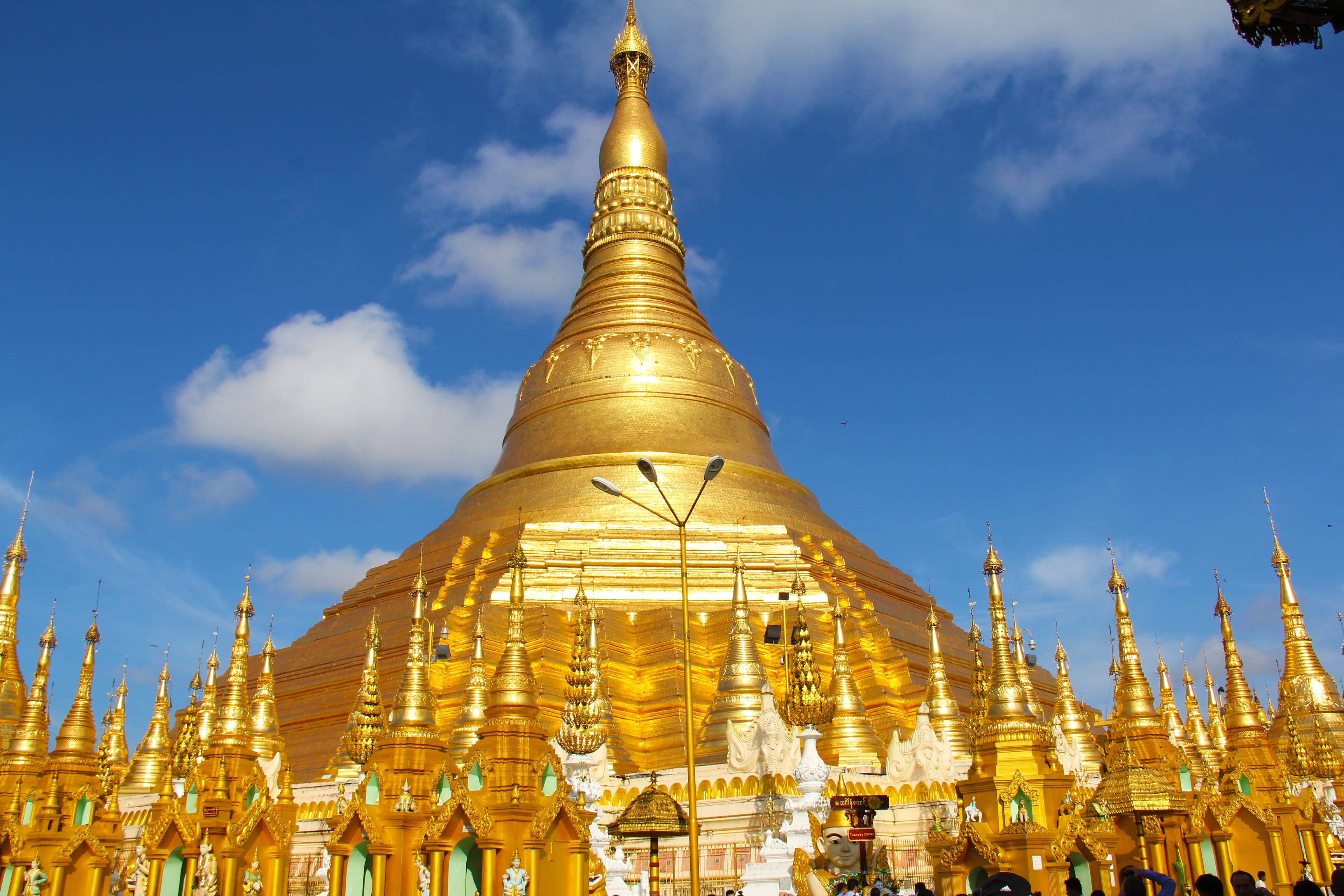Yangon 桌布 壁紙 — 一座雄偉的金色寶塔在明亮的藍天和蓬鬆的白雲下閃閃發光。