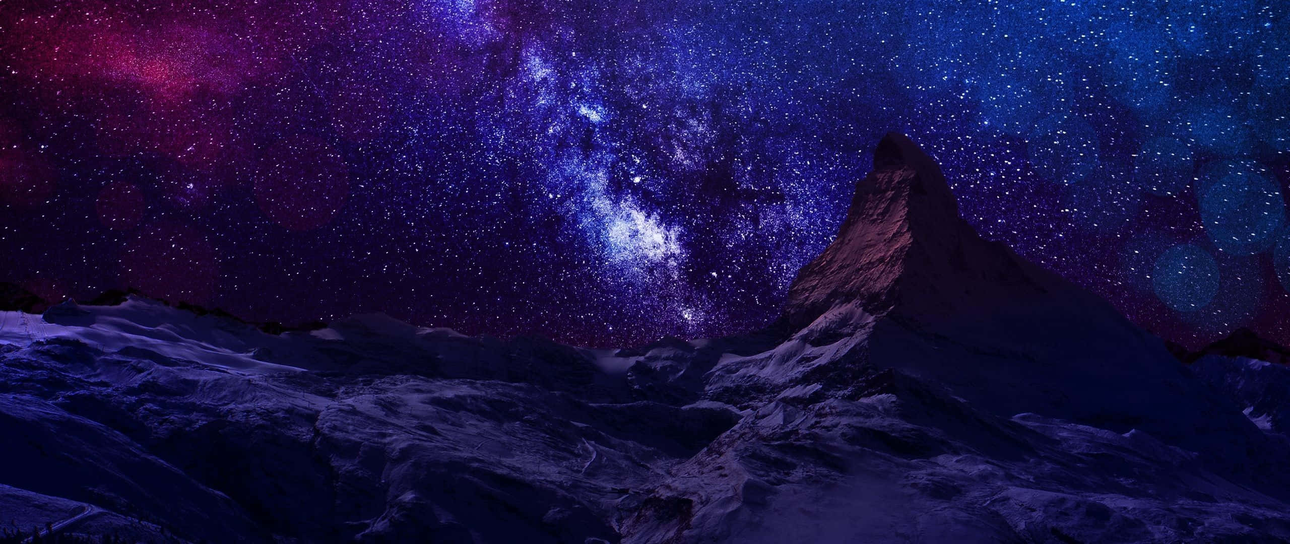 夜空 桌布 壁紙 — 一座雄偉的雪山山峰在充滿銀河系的鮮豔紫色和藍色星空下升起。