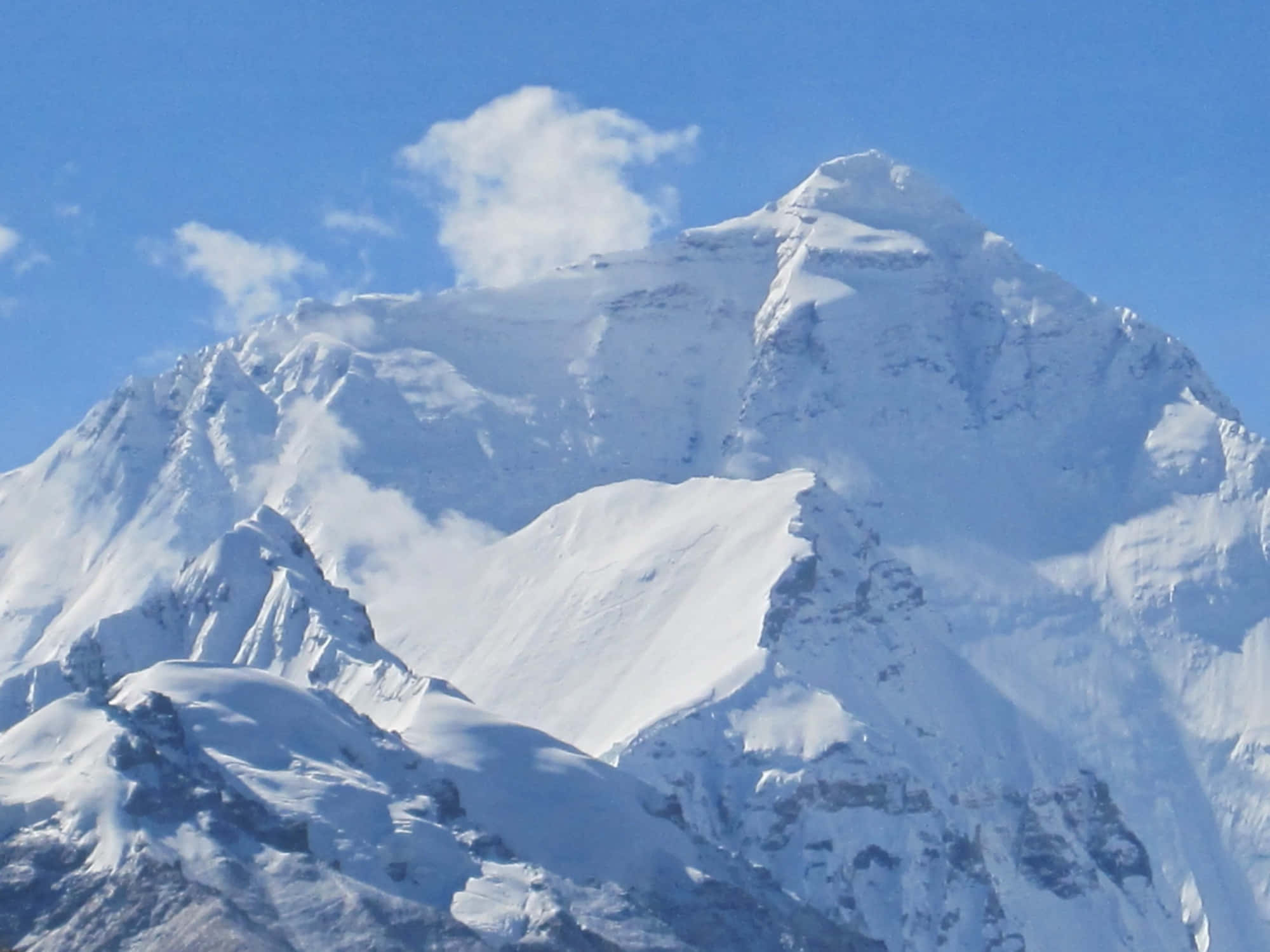 Mount Everest 桌布 壁紙 — 一座雄偉的雪山山峰在晴朗的藍天和飄逸的薄雲襯托下巍然聳立。