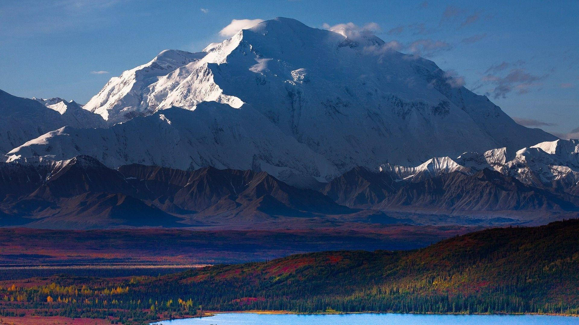 山景 桌布 壁紙 — 一座雄偉的雪山聳立在充滿活力的秋谷之上，下方是平靜的藍色湖泊。