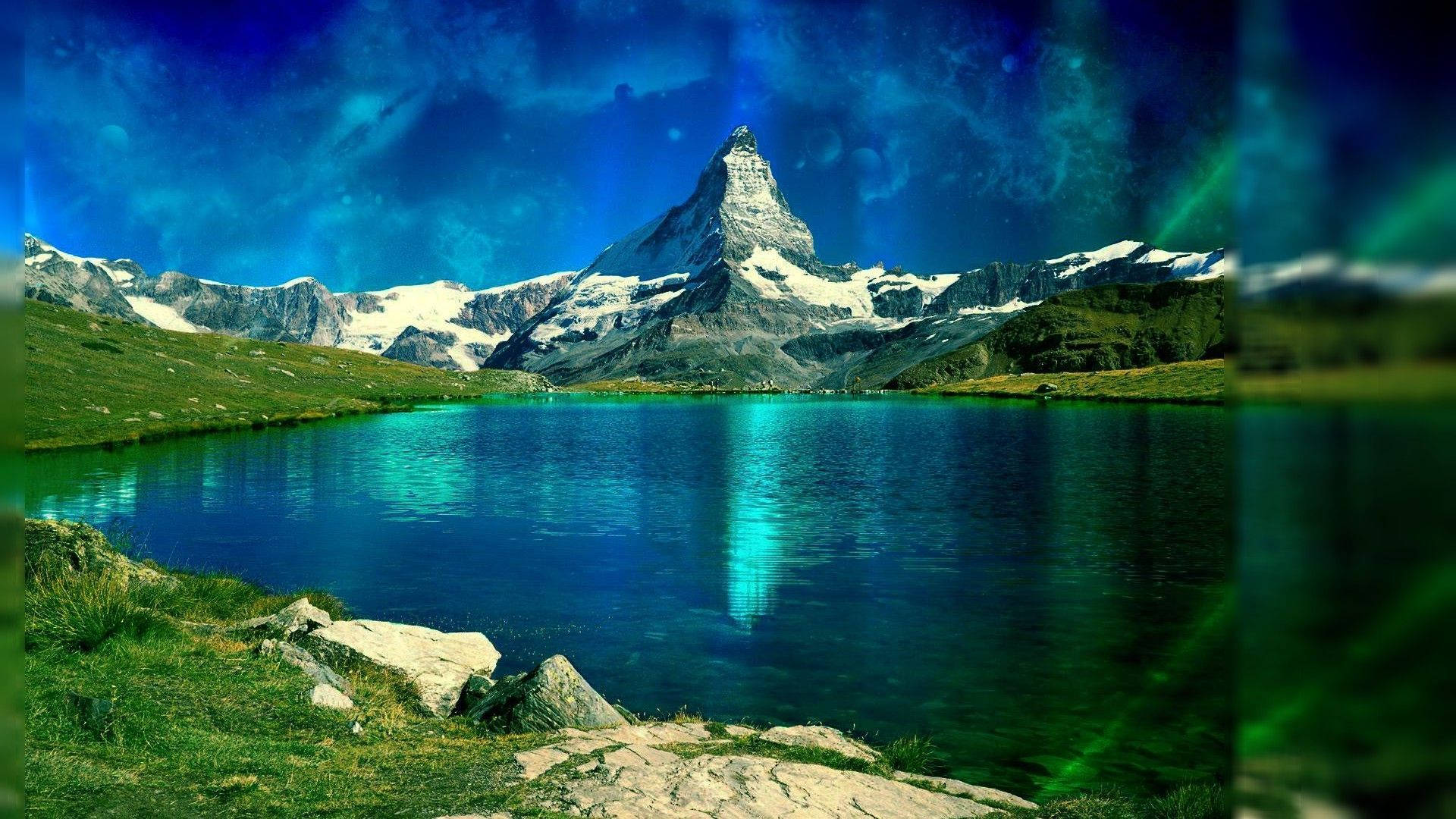 山景 桌布 壁紙 — 一座雄偉的雪山聳立在充滿活力的綠松石湖之上，天空蔚藍壯麗，帶有極光般的光芒。