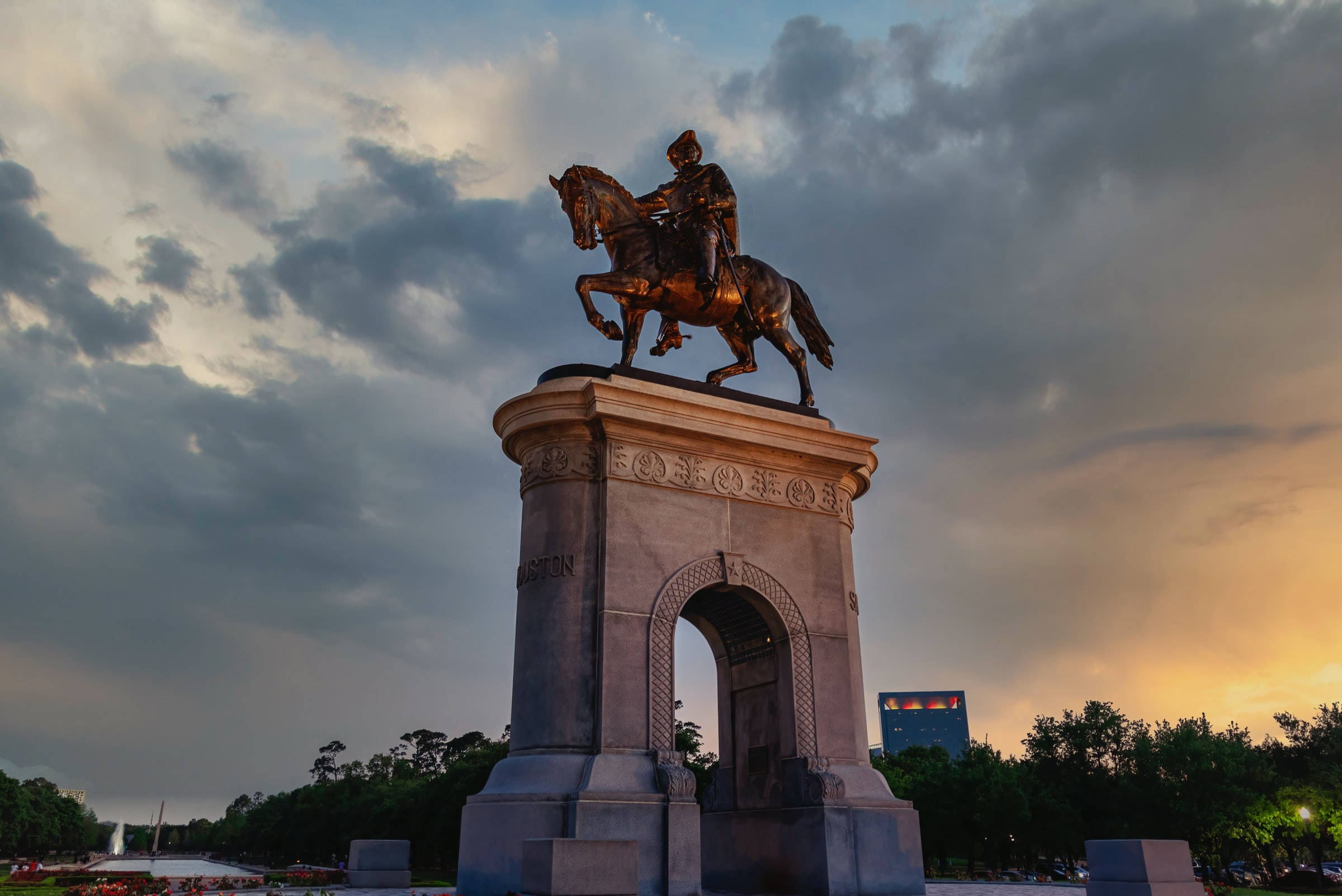 Houston 桌布 壁紙 — 一座雄偉的青銅騎馬雕像矗立在石拱門上，在佈滿散雲的戲劇性暮色天空下閃耀。