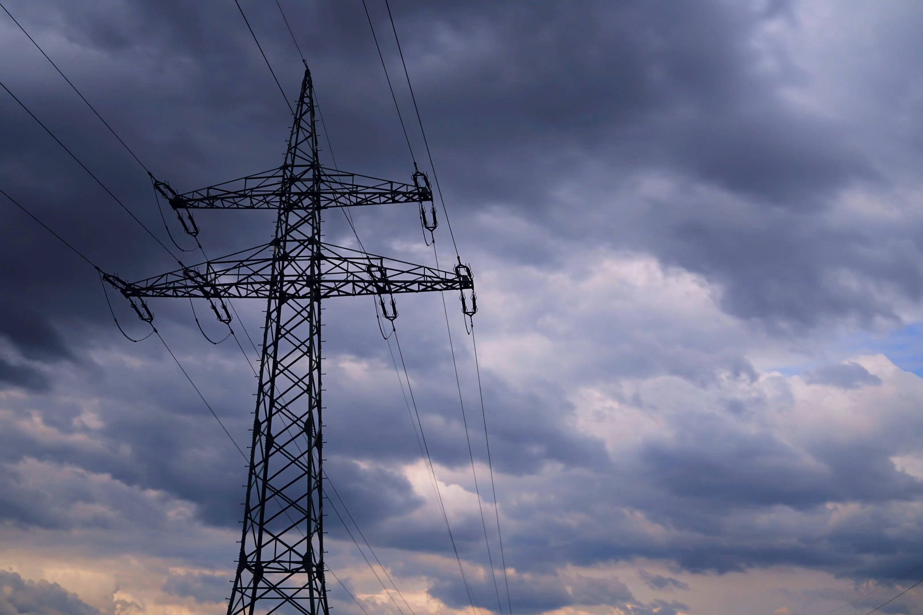 Electricity 桌布 壁紙 — 一座電塔的鮮明剪影矗立在黃昏時分戲劇性的多雲天空下。