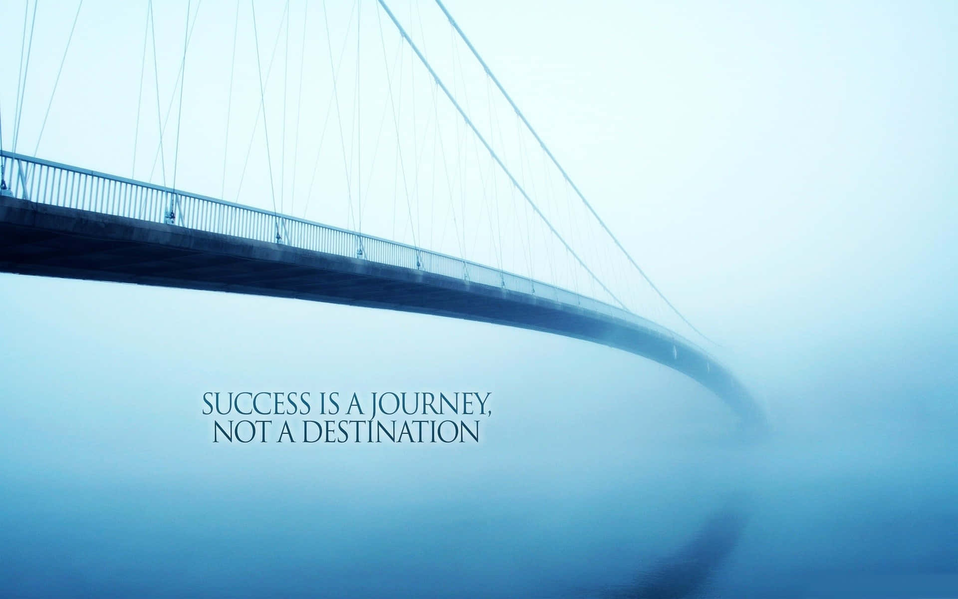 Positive Quotes 桌布 壁紙 — 一座霧氣瀰漫的吊橋彎曲進入霧中，上面覆蓋著一句名言：成功是一段旅程，而不是目的地。