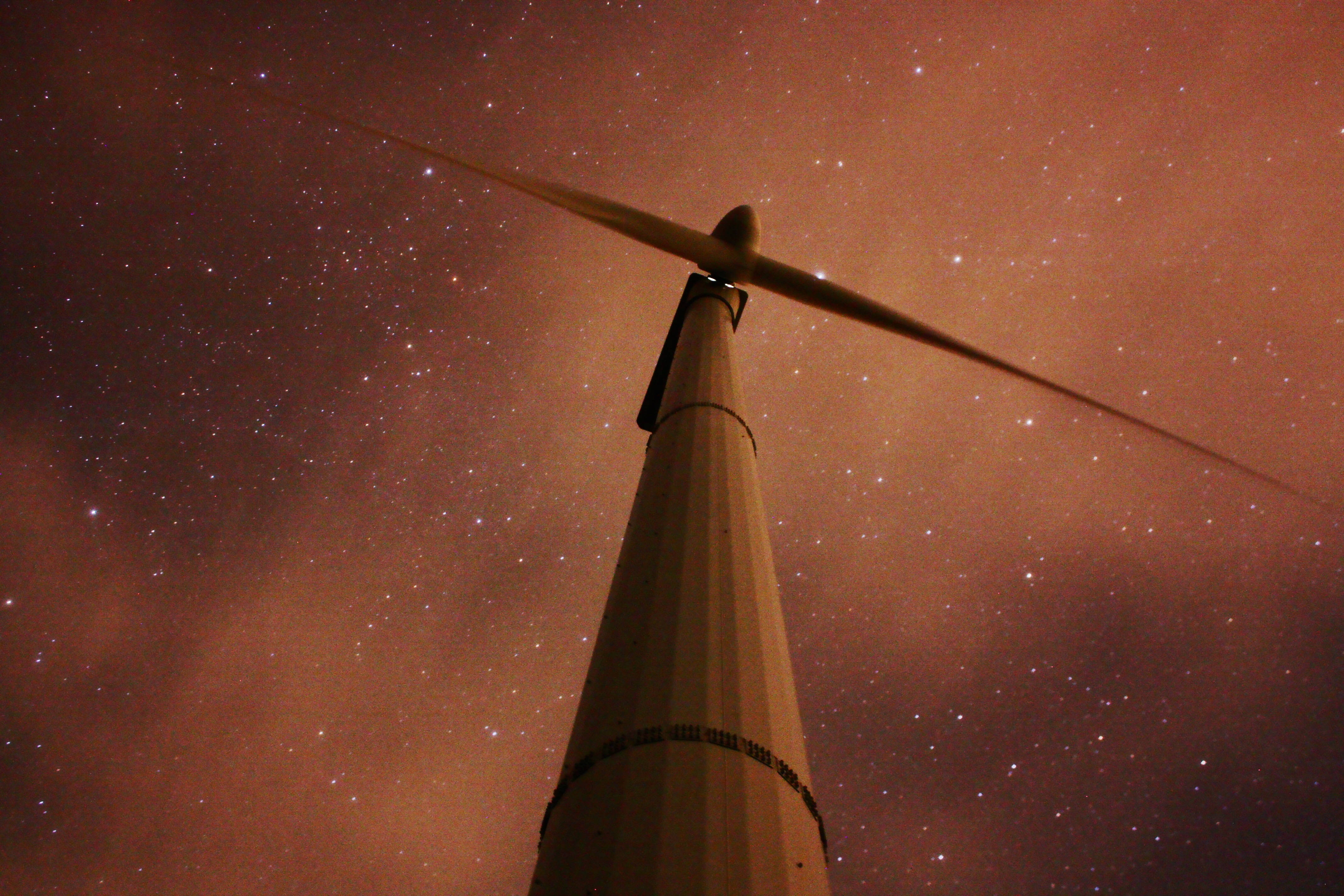 Energy 桌布 壁紙 — 一座風力渦輪機高聳在溫暖橙色光芒的星空夜空背景下。