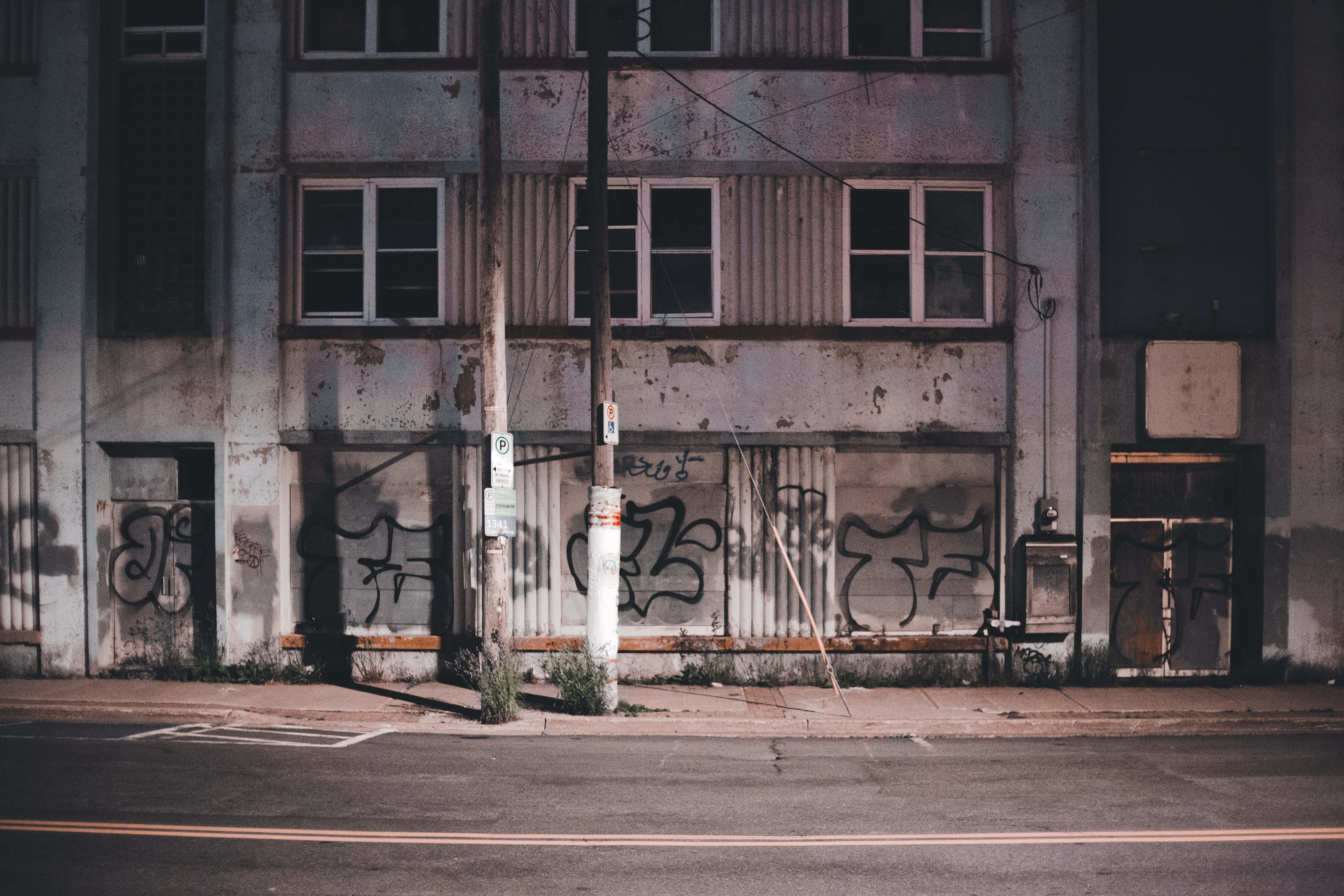 Abandoned 桌布 壁紙 — 一座風化的城市建築，牆上佈滿塗鴉，在昏暗的暮光下，在寧靜的街道上投下長長的陰影。