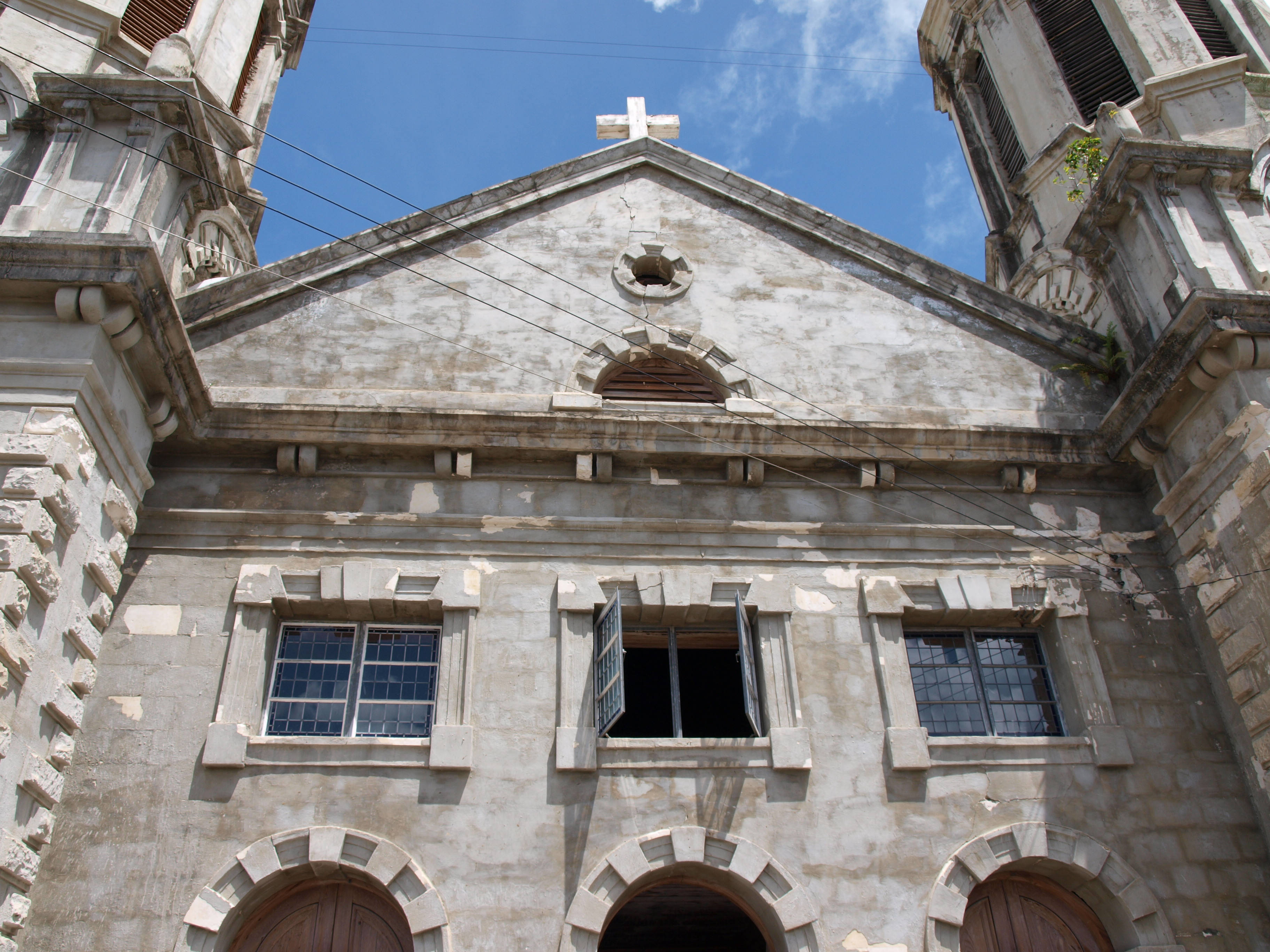 Antigua And Barbuda 桌布 壁紙 — 一座風化的石砌教堂外牆，帶有拱形門口和破損窗戶，在明亮的藍天下。