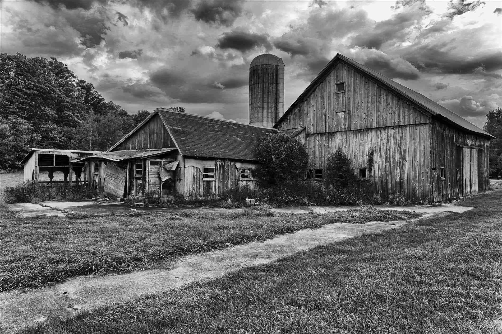 Old Farm 桌布 壁紙 — 一座風化的穀倉和筒倉在戲劇性的多雲天空下以單色被遺棄。