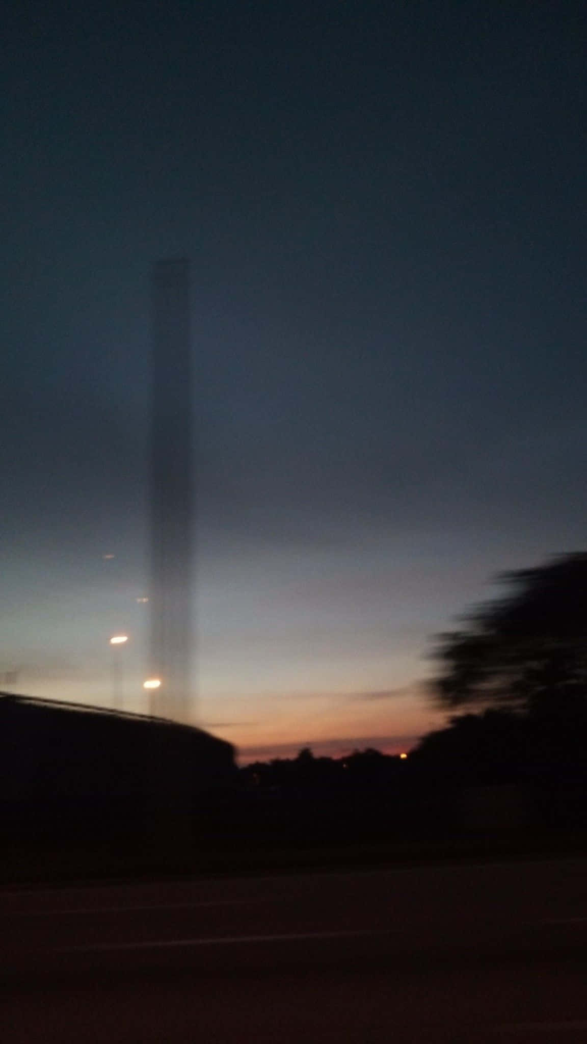 手機 桌布 壁紙 — 一座高塔在暮色天空的襯托下呈現剪影，地平線附近帶有柔和的橙色和紫色色調。