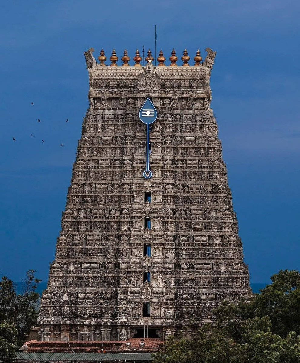 Hindu Temple 桌布 壁紙 — 一座高聳、雕刻精美的石廟塔樓（gopuram）在深藍色的天空下聳立，附近有鳥兒飛翔。