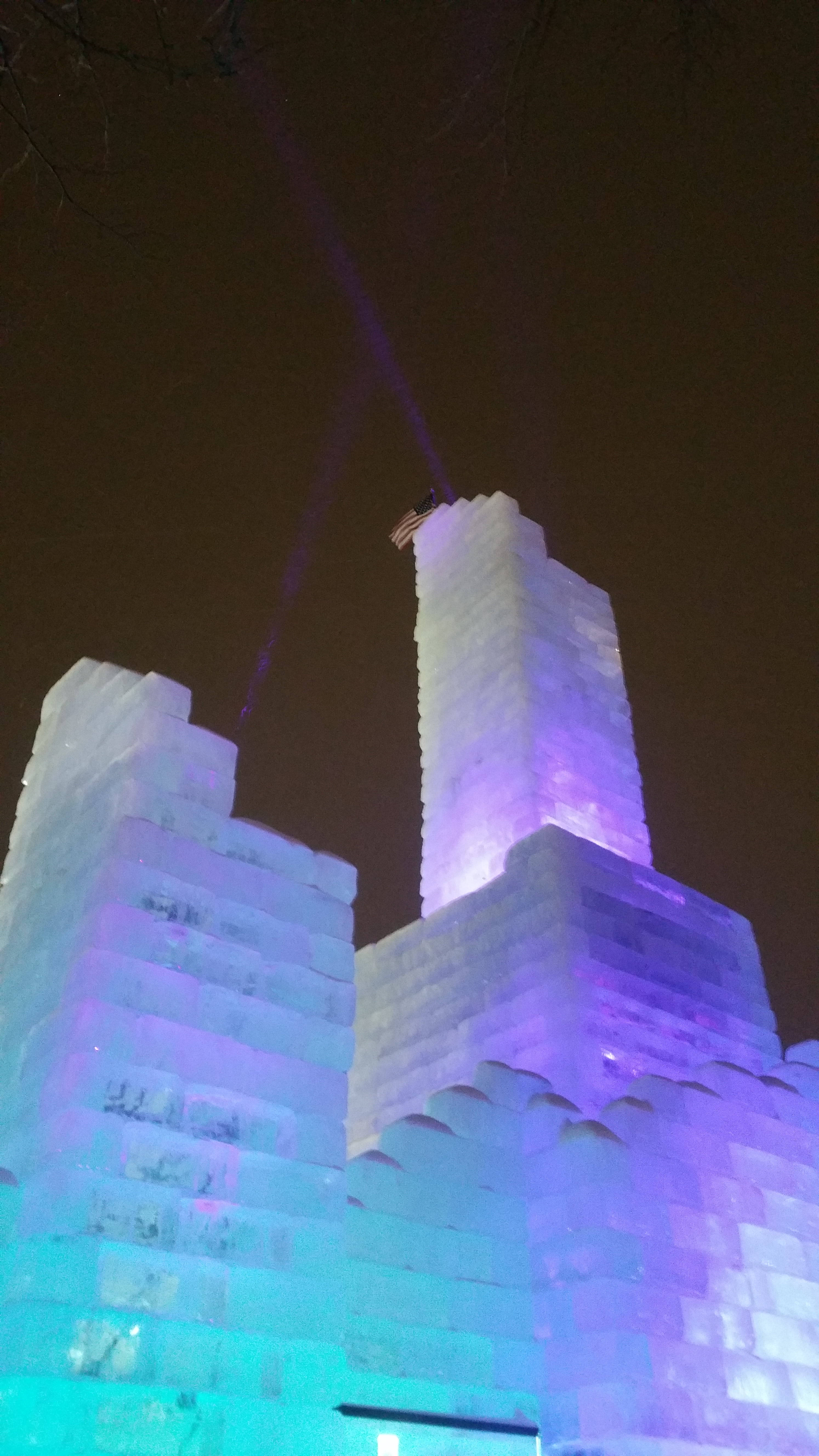 冰雪城堡 桌布 壁紙 — 一座高聳的冰雕，在黑暗的夜空下以鮮豔的藍色和紫色燈光照明。