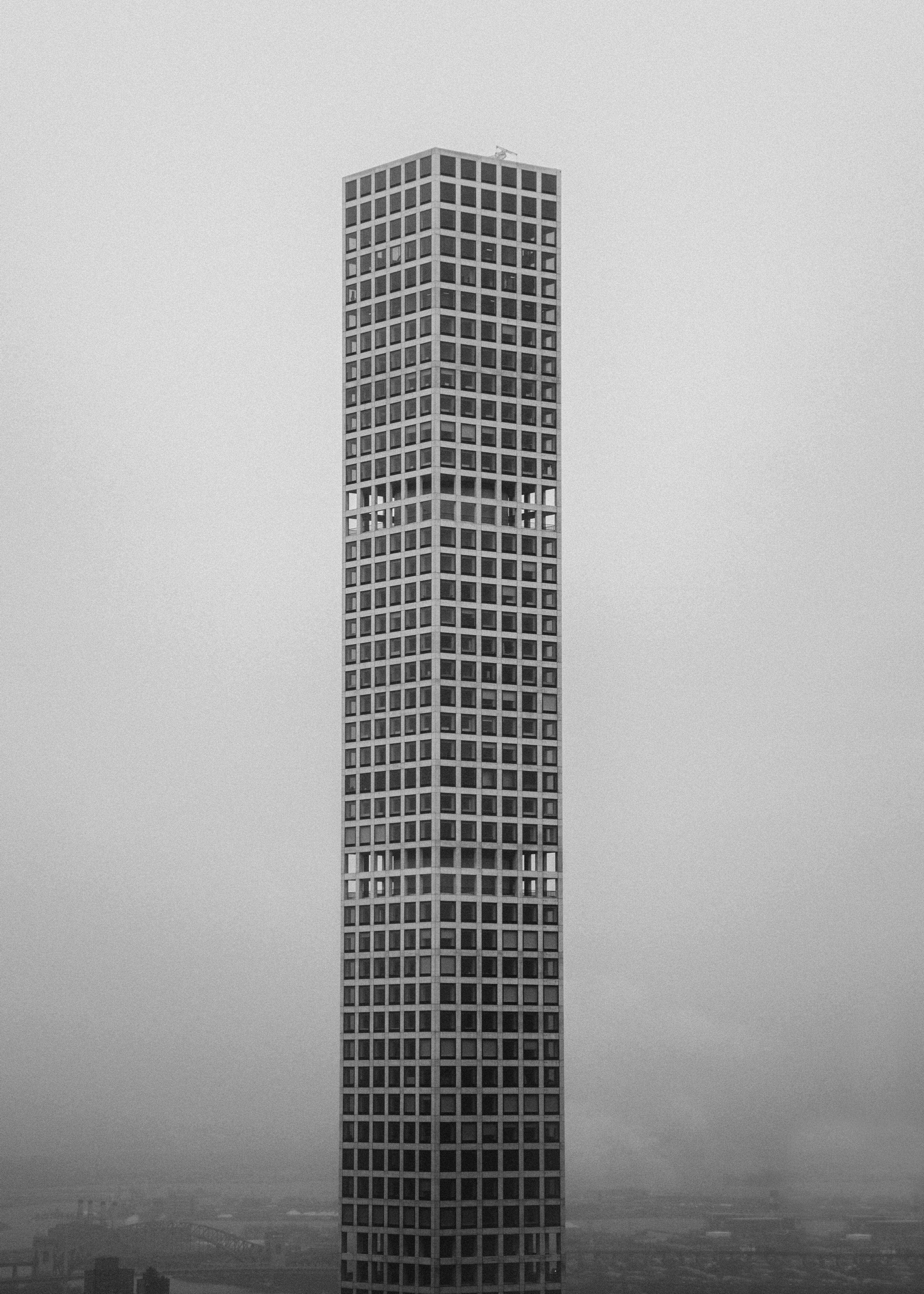 Building 桌布 壁紙 — 一座高聳的單體摩天大樓刺穿灰濛濛的天空，呈現出鮮明的黑白城市景觀。