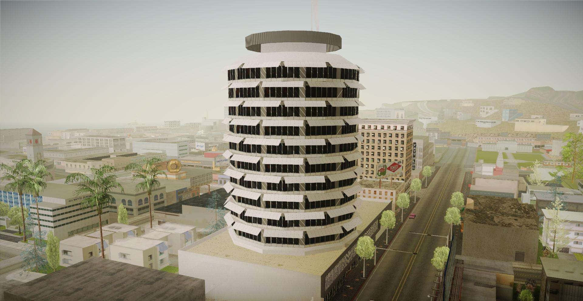 3D 桌布 壁紙 — 一座高聳的圓柱形辦公大樓，帶有黑色窗帶，主宰著棕櫚樹和遠山籠罩的朦朧城市景觀。