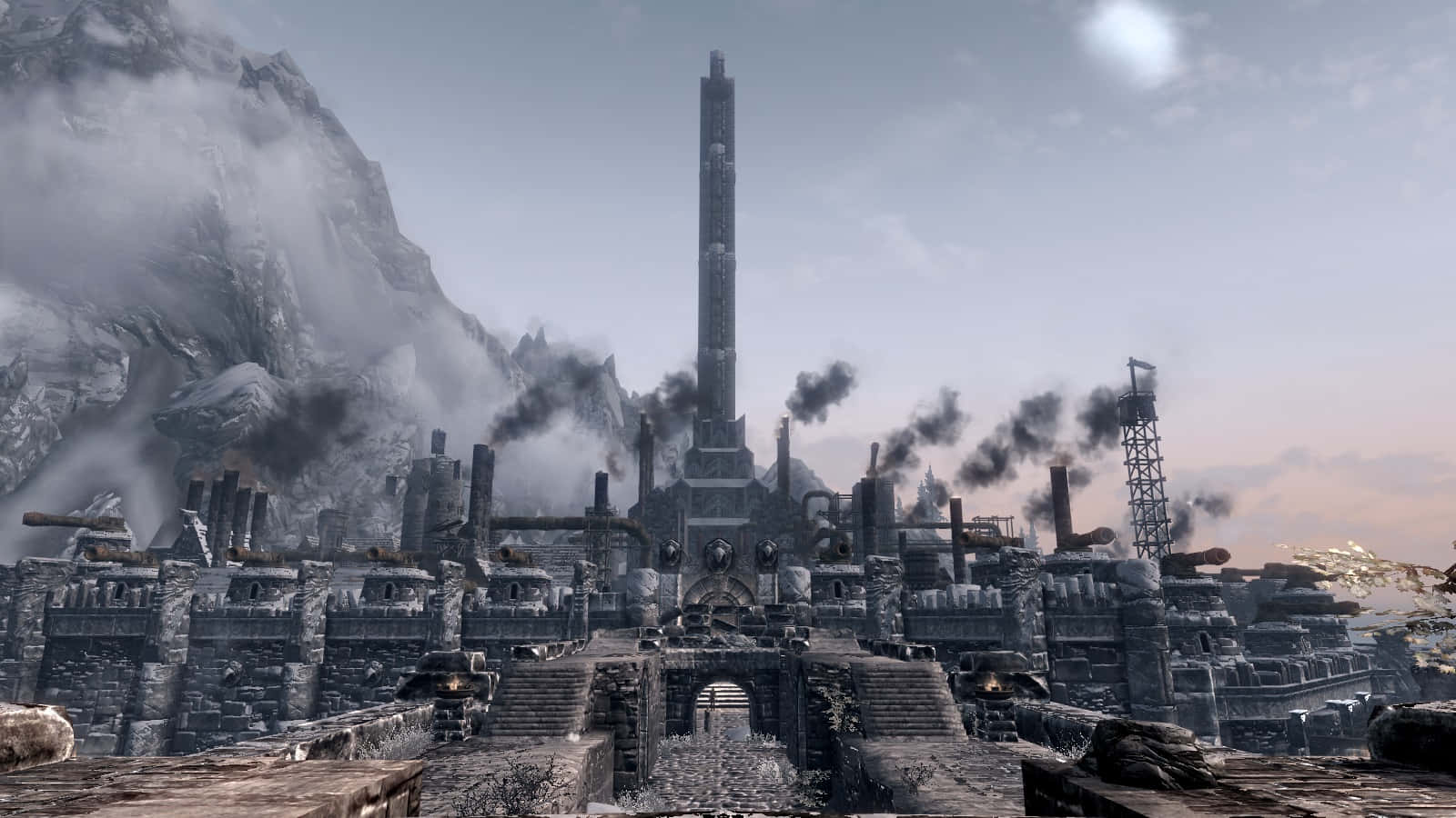 Skyrim Windhelm 桌布 壁紙 — 一座高聳的工業綜合體在蒼白的暮色天空下，於白雪覆蓋的山脈中冒煙。