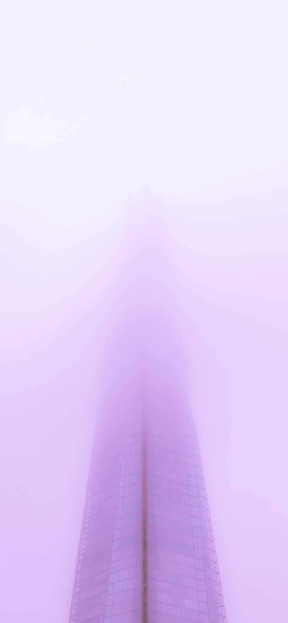 Purple Phone 桌布 壁紙 — 一座高聳的摩天大樓在極簡的城市景觀中刺穿朦朧的薰衣草色天空。