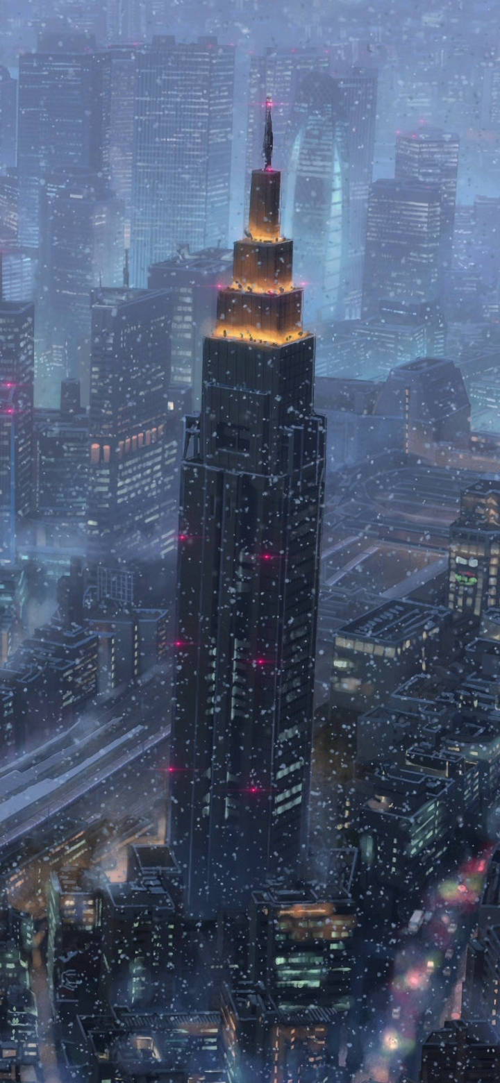 東京 桌布 壁紙 — 一座高聳的摩天大樓在雪夜的城市天際線中溫暖地發光，雪花飄落，城市燈光閃爍。