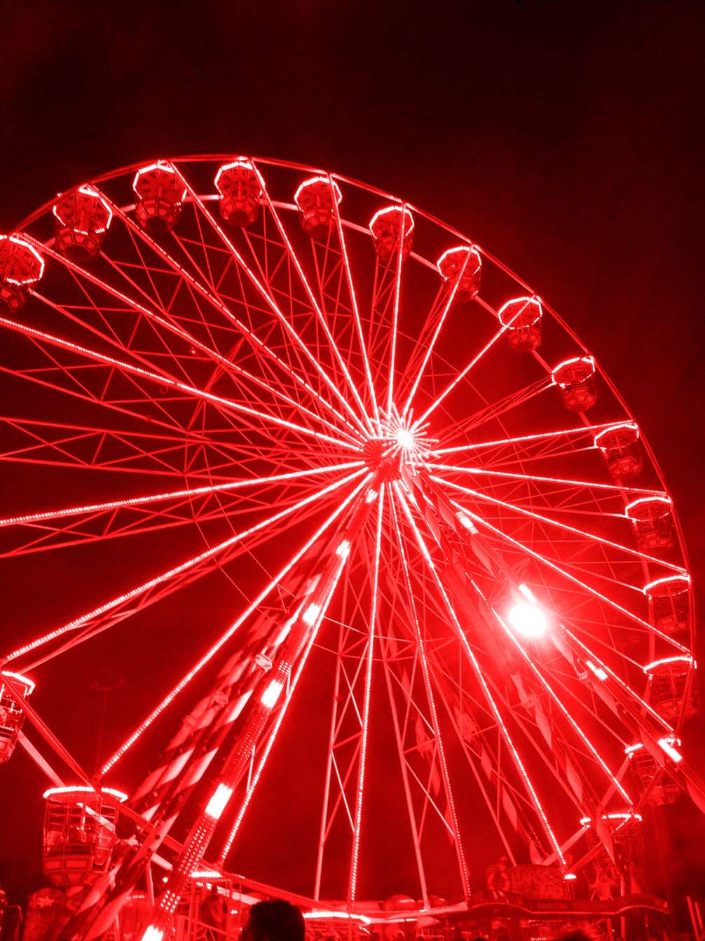 Neon Red Aesthetic 桌布 壁紙 — 一座高聳的摩天輪在漆黑的夜空中發出強烈的紅光，其發光的結構投射出耀眼的光芒。