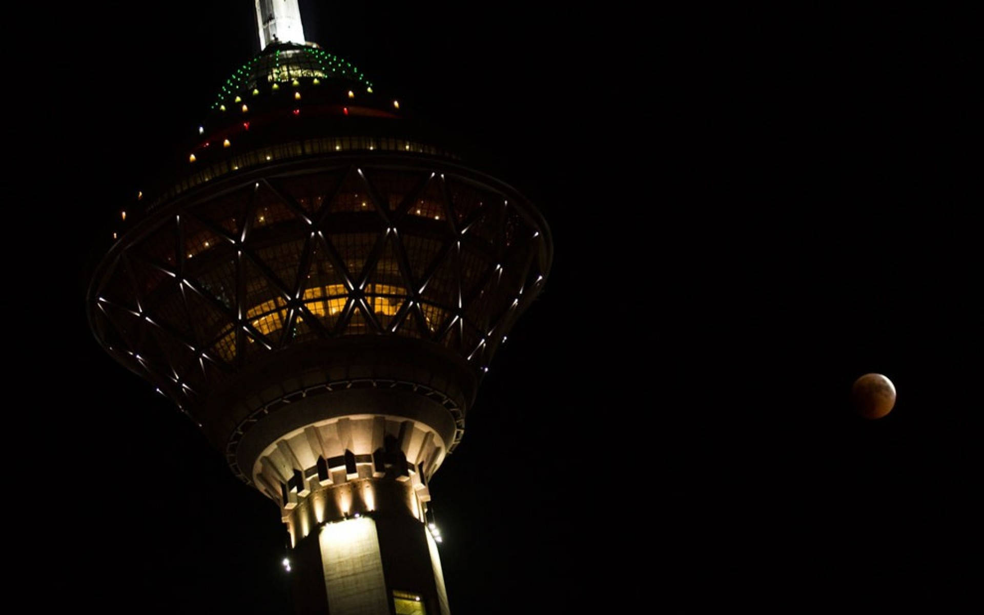 Tehran 桌布 壁紙 — 一座高聳的照明建築矗立在黑暗的夜空下，附近有一輪發光的月亮。