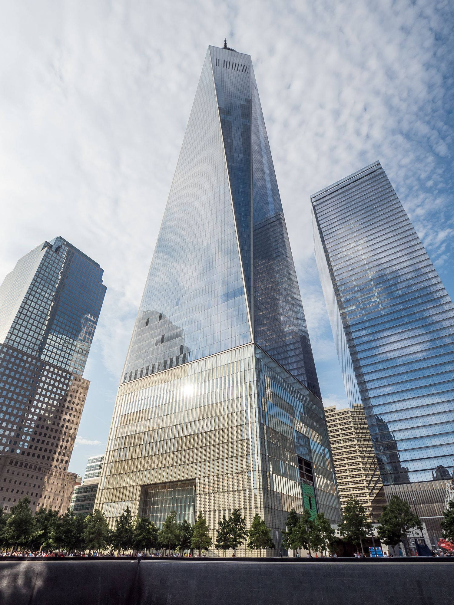 Skyscraper 桌布 壁紙 — 一座高聳的玻璃摩天大樓，帶有反光外牆，在部分多雲的天空下主導著城市天際線。