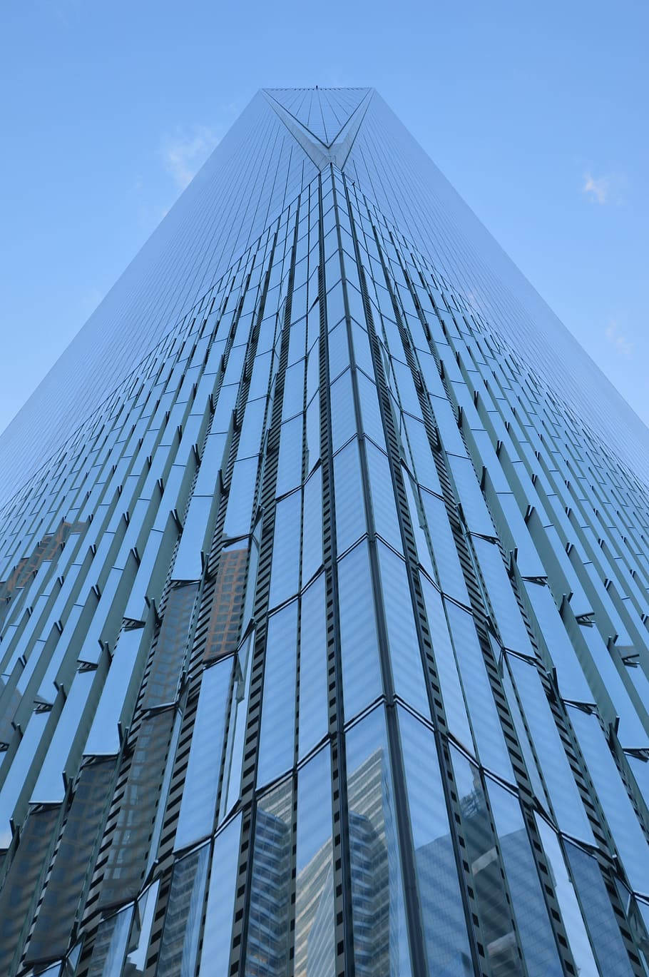 Skyscraper 桌布 壁紙 — 一座高聳的玻璃摩天大樓，帶有尖銳的三角形頂峰，在低角度拍攝下，聳立在清澈的藍天中。