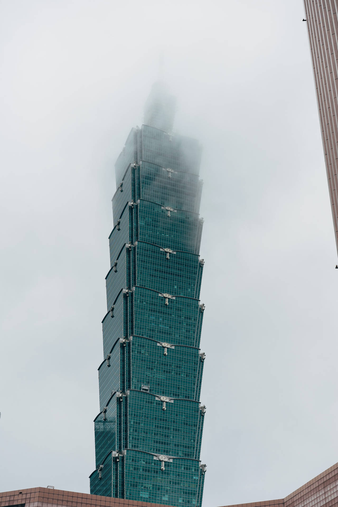 現代玻璃摩天大樓在多雲天氣下部分被霧雲遮擋。