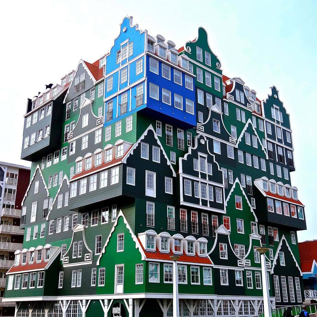 Building 桌布 壁紙 — 一座高聳的現代飯店，堆疊著色彩繽紛的荷蘭式山牆房屋，以綠色、藍色和灰色為主色調，在蒼白的天空下。