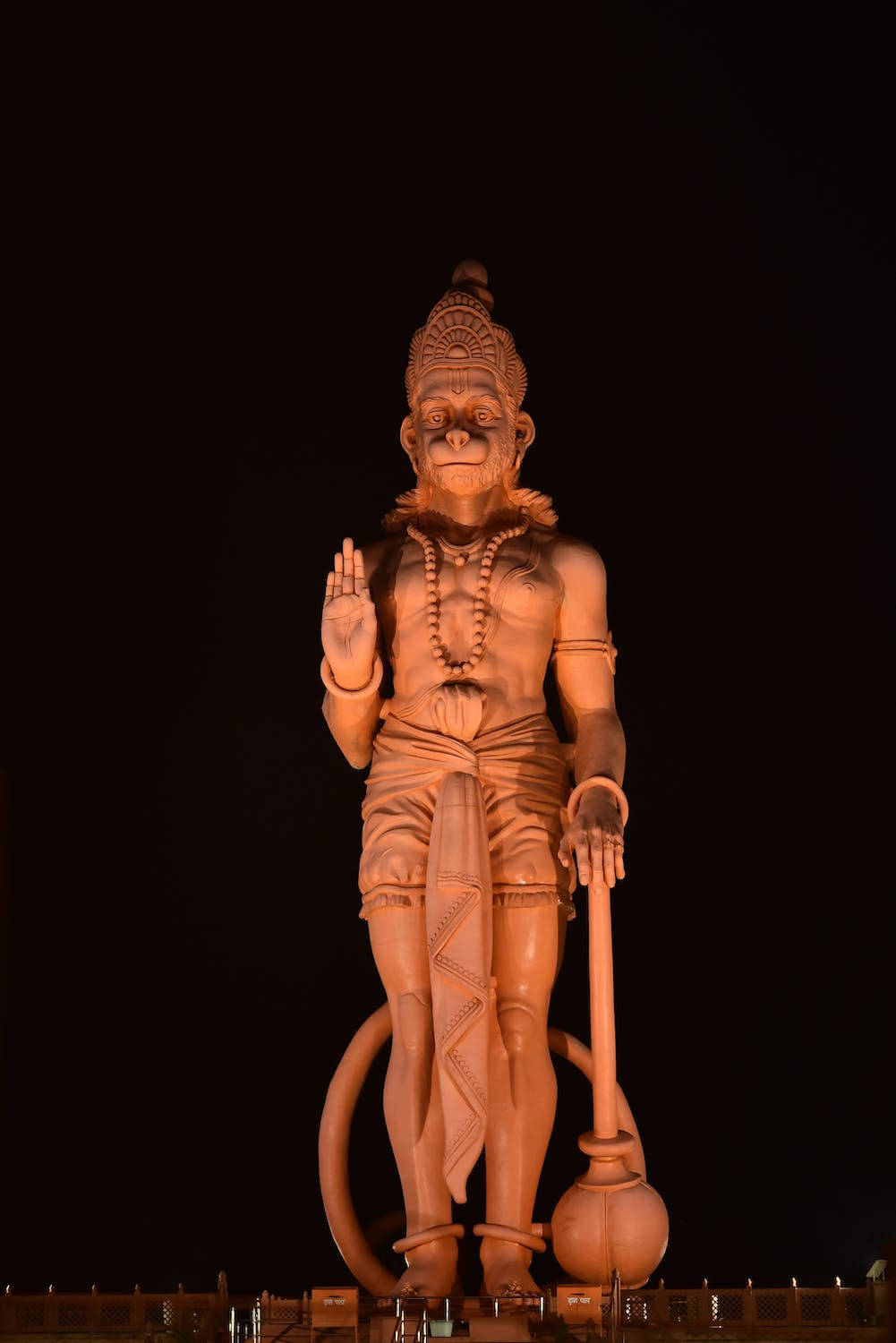 statue 桌布 壁紙 — 一座高聳的發光哈努曼雕像在漆黑的夜空中威嚴矗立，溫暖的金色燈光突顯了複雜的細節。