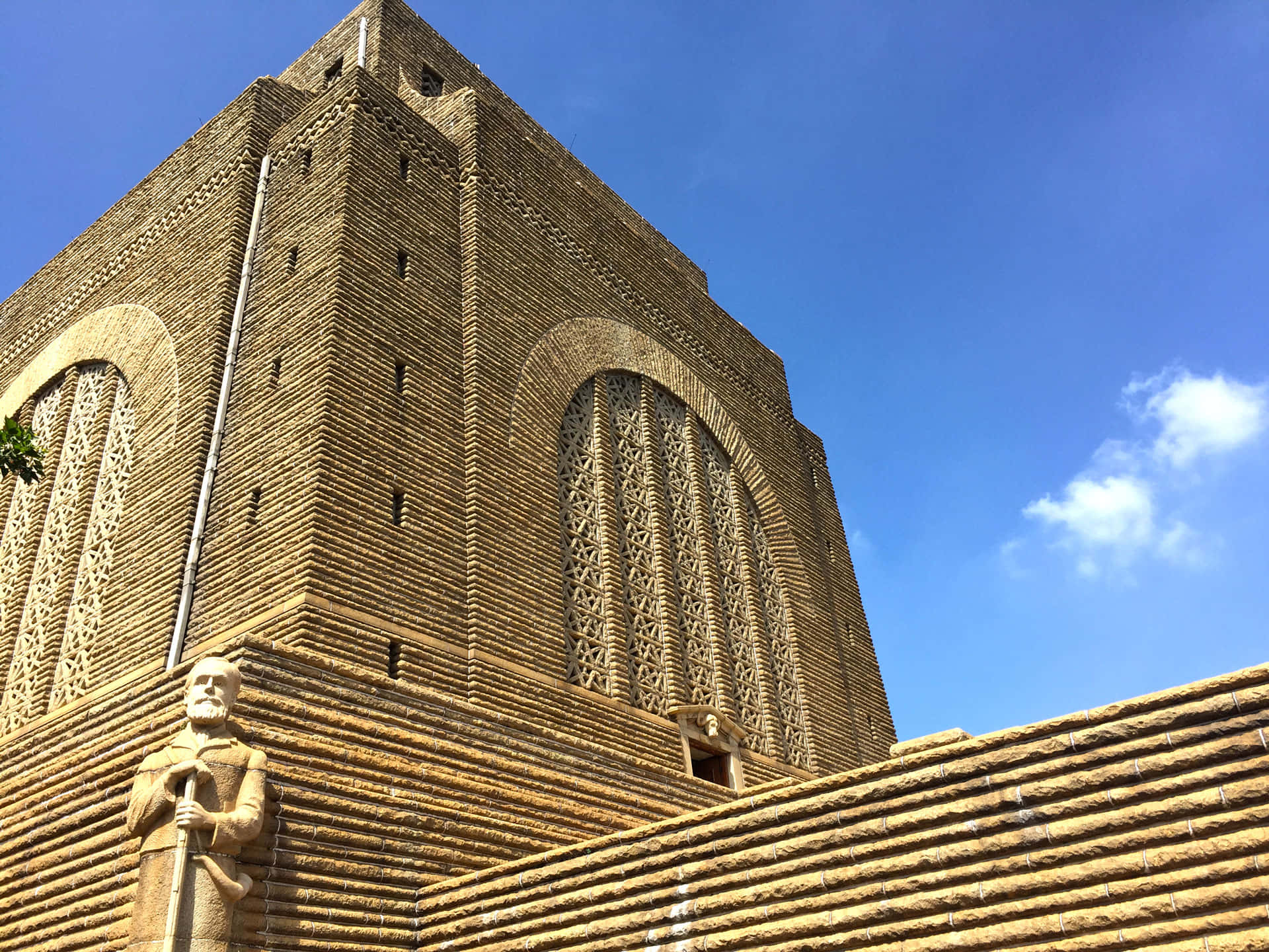 Architecture 桌布 壁紙 — 一座高聳的磚砌建築，帶有精緻的拱形窗戶和一座雕像，矗立在晴朗的藍天和白雲之下。
