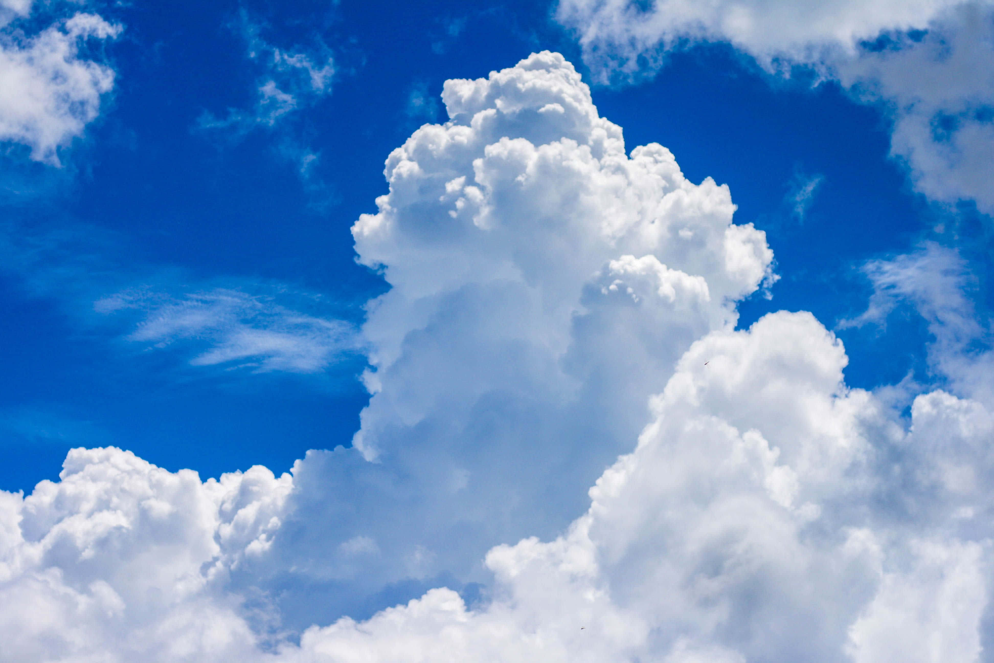 Clouds Aesthetics 桌布 壁紙 — 一座高聳的積雲主宰著一片充滿活力的藍天，點綴著散落的薄雲。