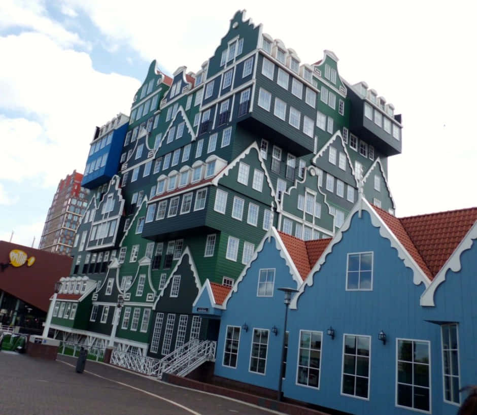 Hotel 桌布 壁紙 — 一座高聳的綠色和藍色建築，帶有傳統的山牆屋頂和白色飾邊，矗立在部分多雲的天空下。